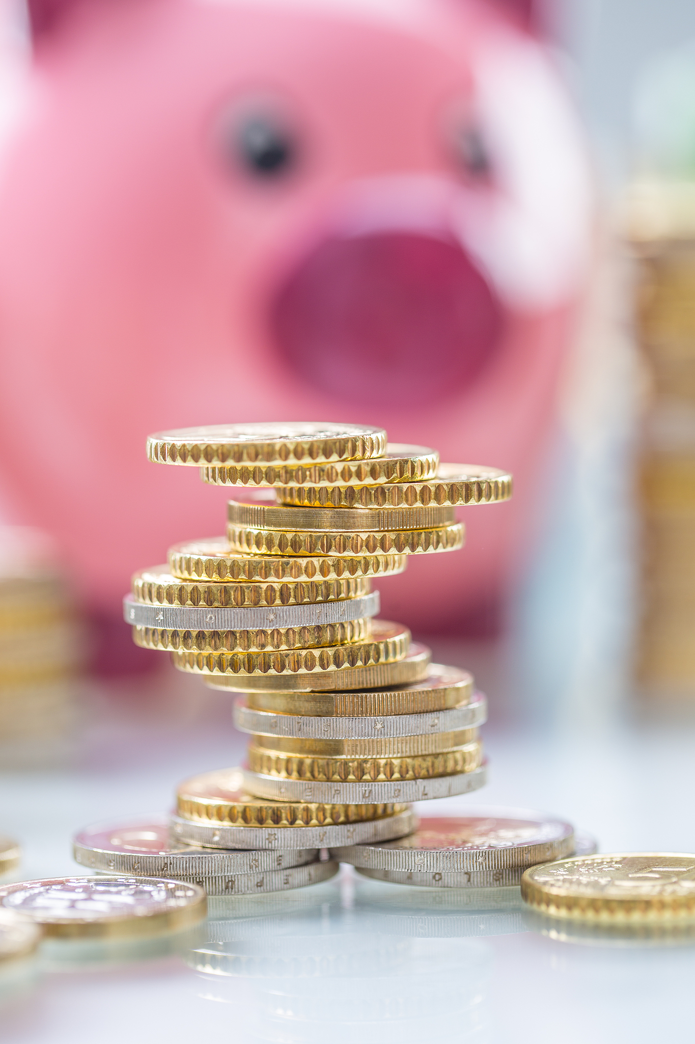 pink piggy bank in the middle of rolled euro banknotes and tower