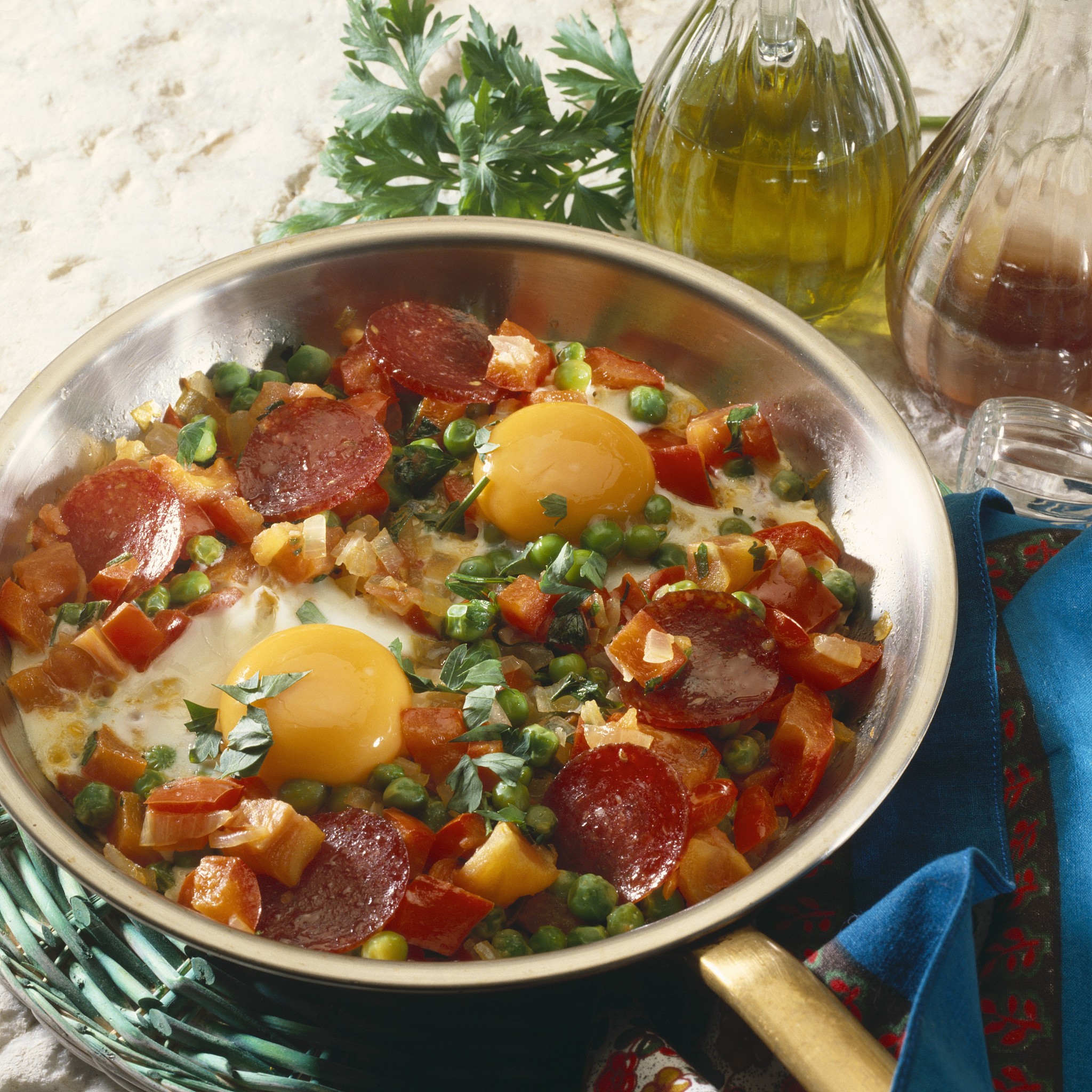 fried eggs, sausage and vegetables in frying pan