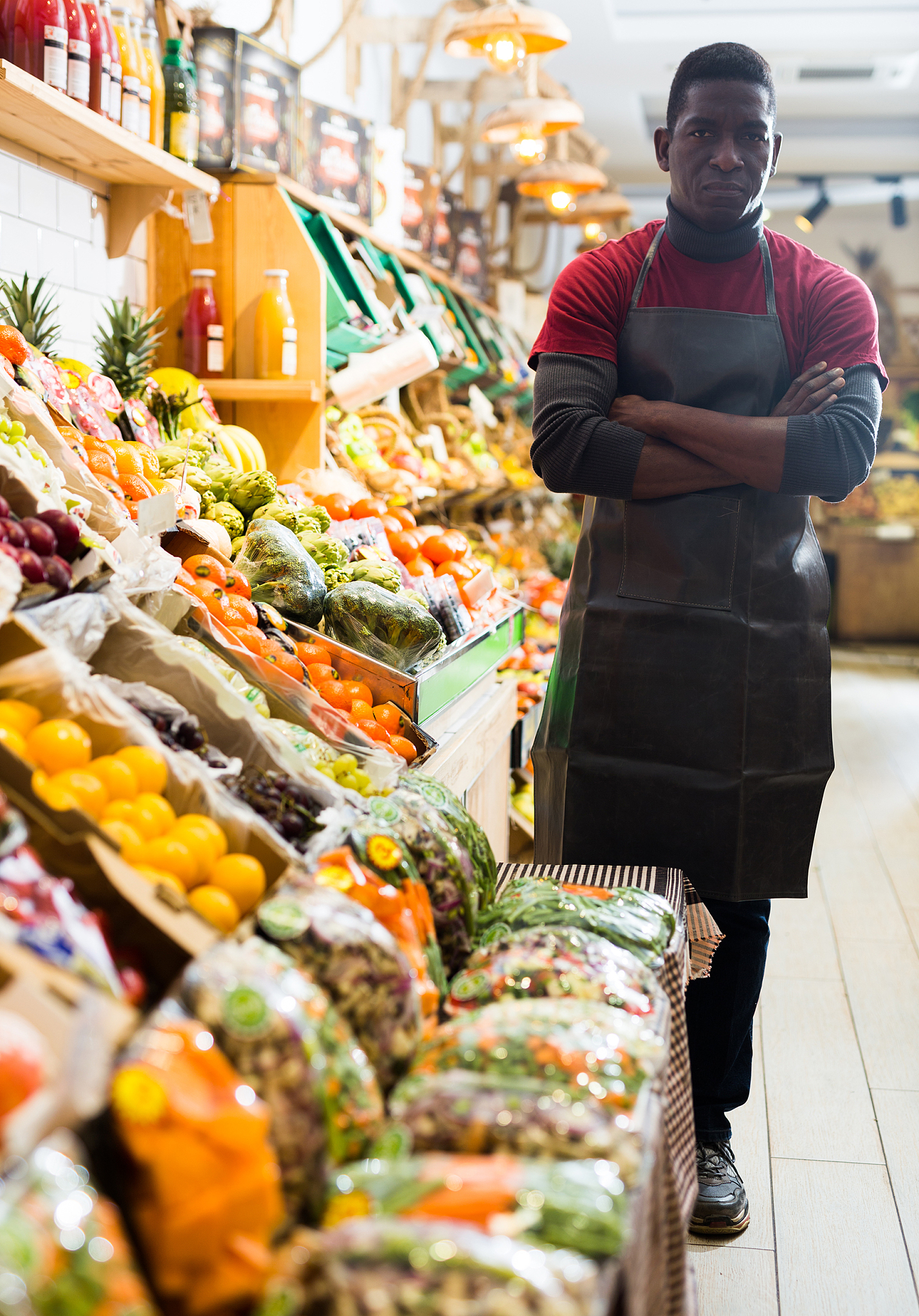 seller of fruits and vegetables store standing with crossed arms