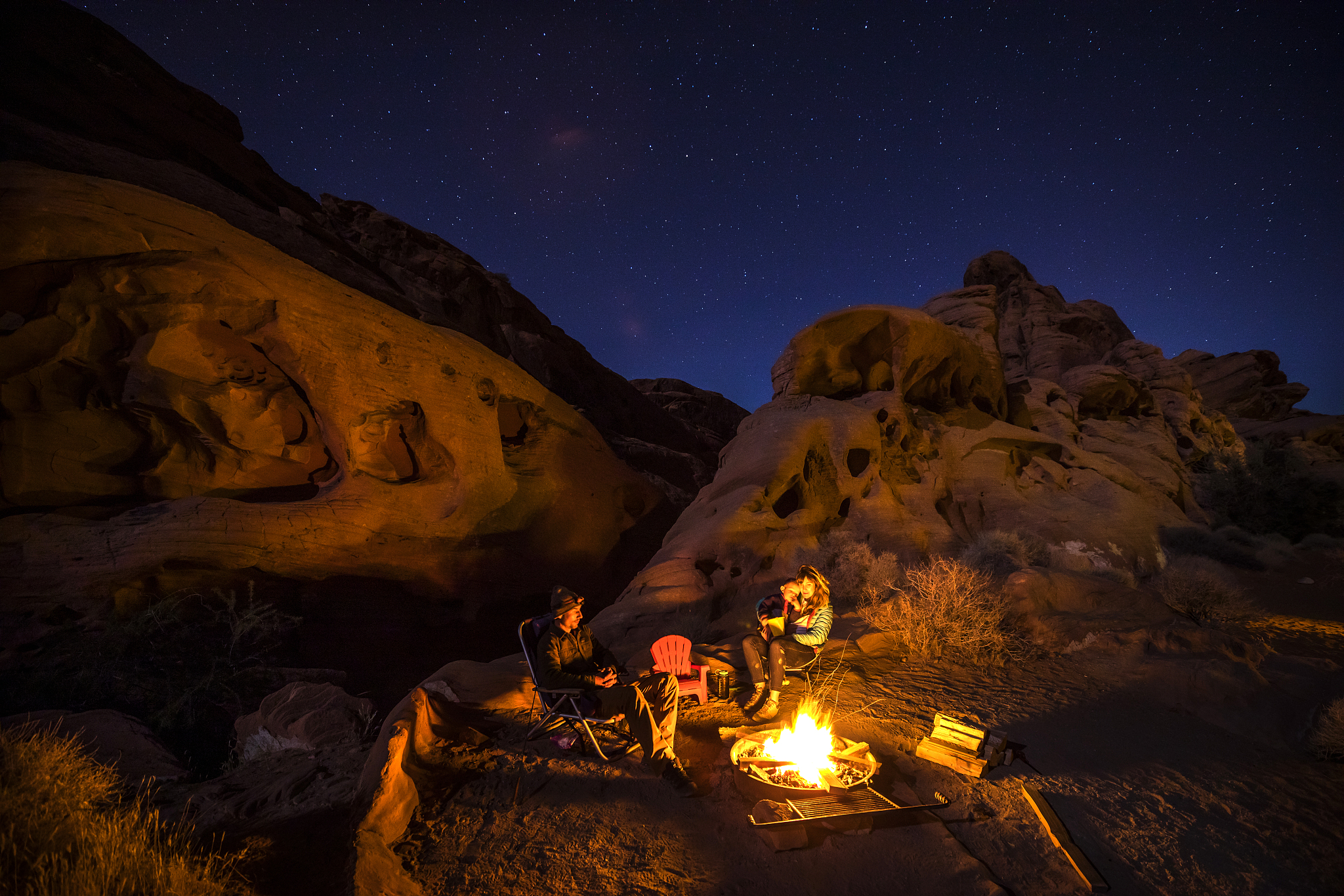 a family of three sitting around a campfire