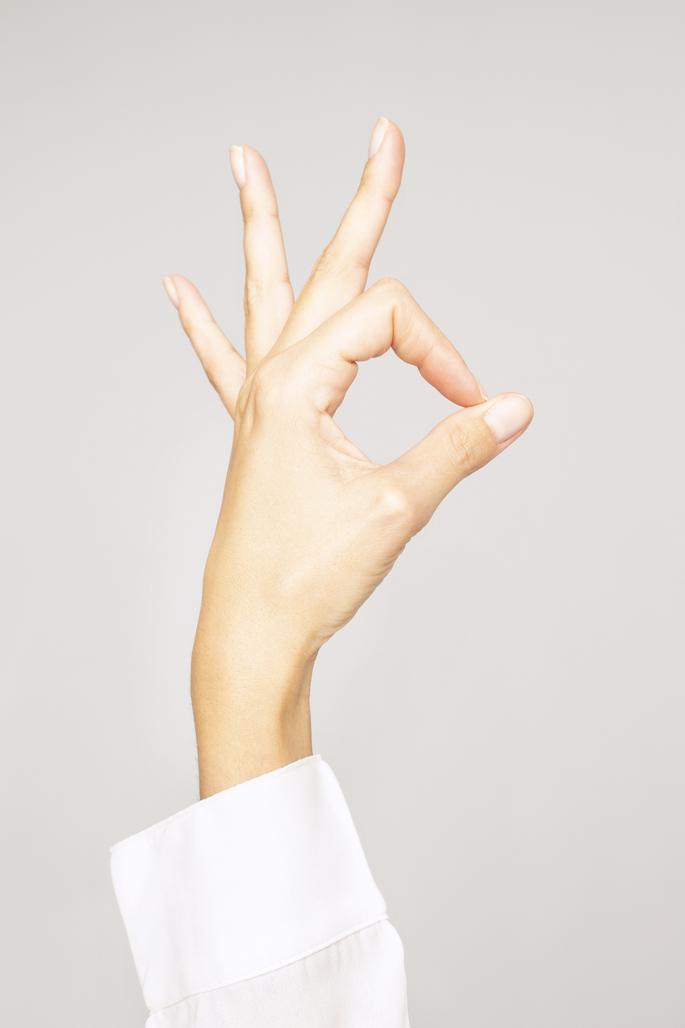 hand of a woman showing three fingers, doing the ok sign