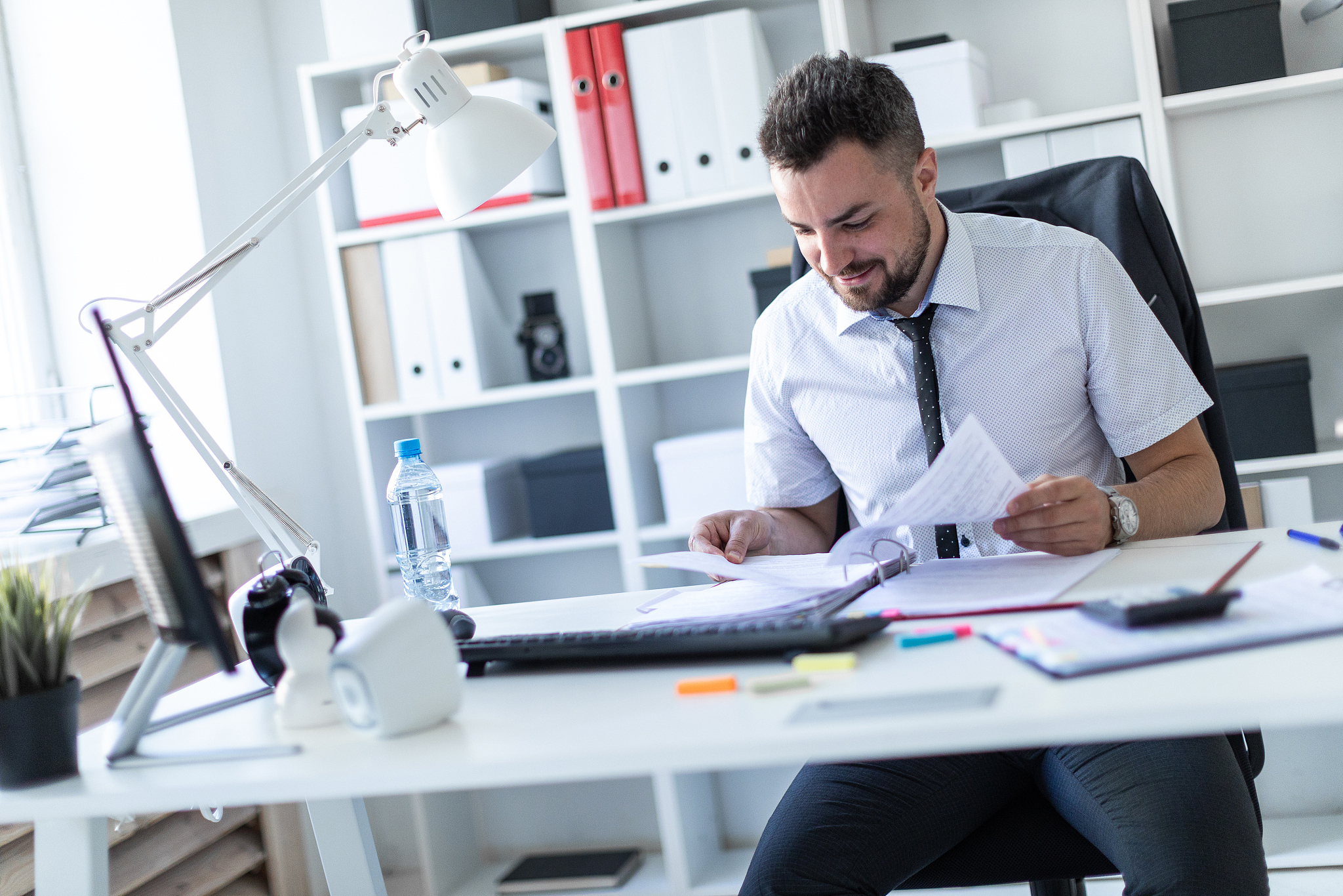 a man is sitting at the desk in the office and working with docu
