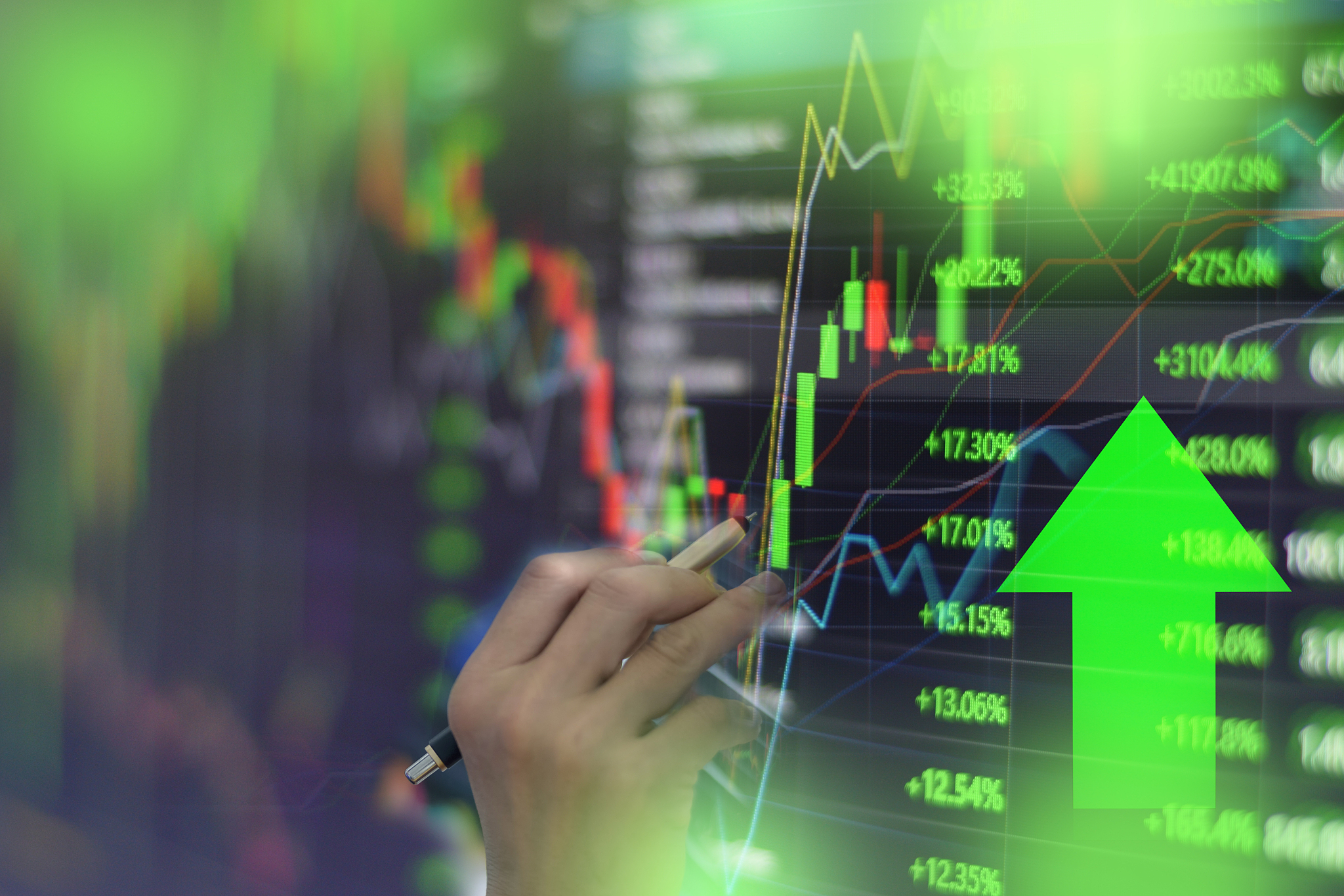 close-up of hand analyzing stock market data on screen