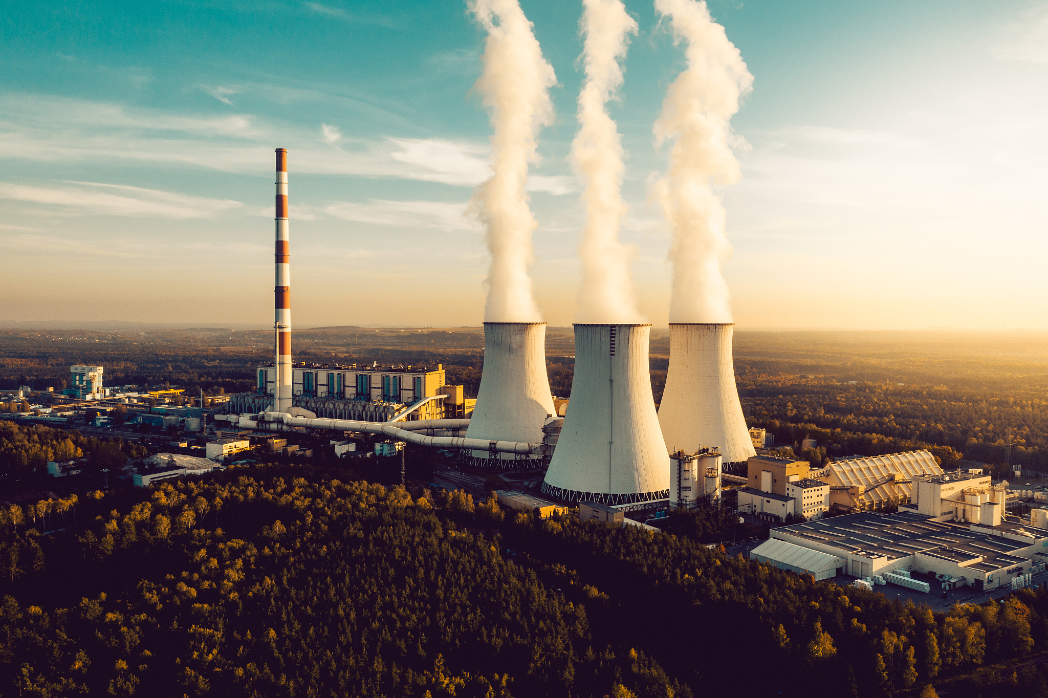 a power plant with white smoke over it's chimneys