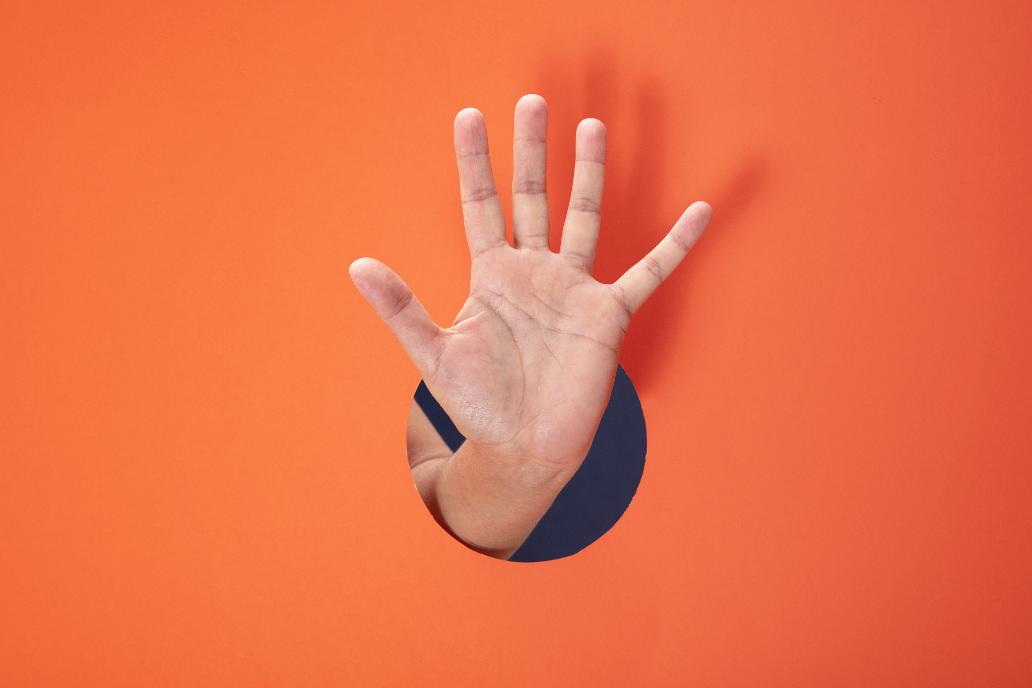 female hand showing number five on orange paper background