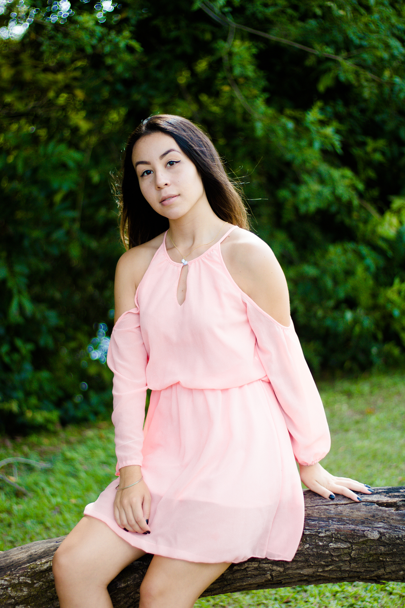 beautiful young woman sitting on tree trunk in forest