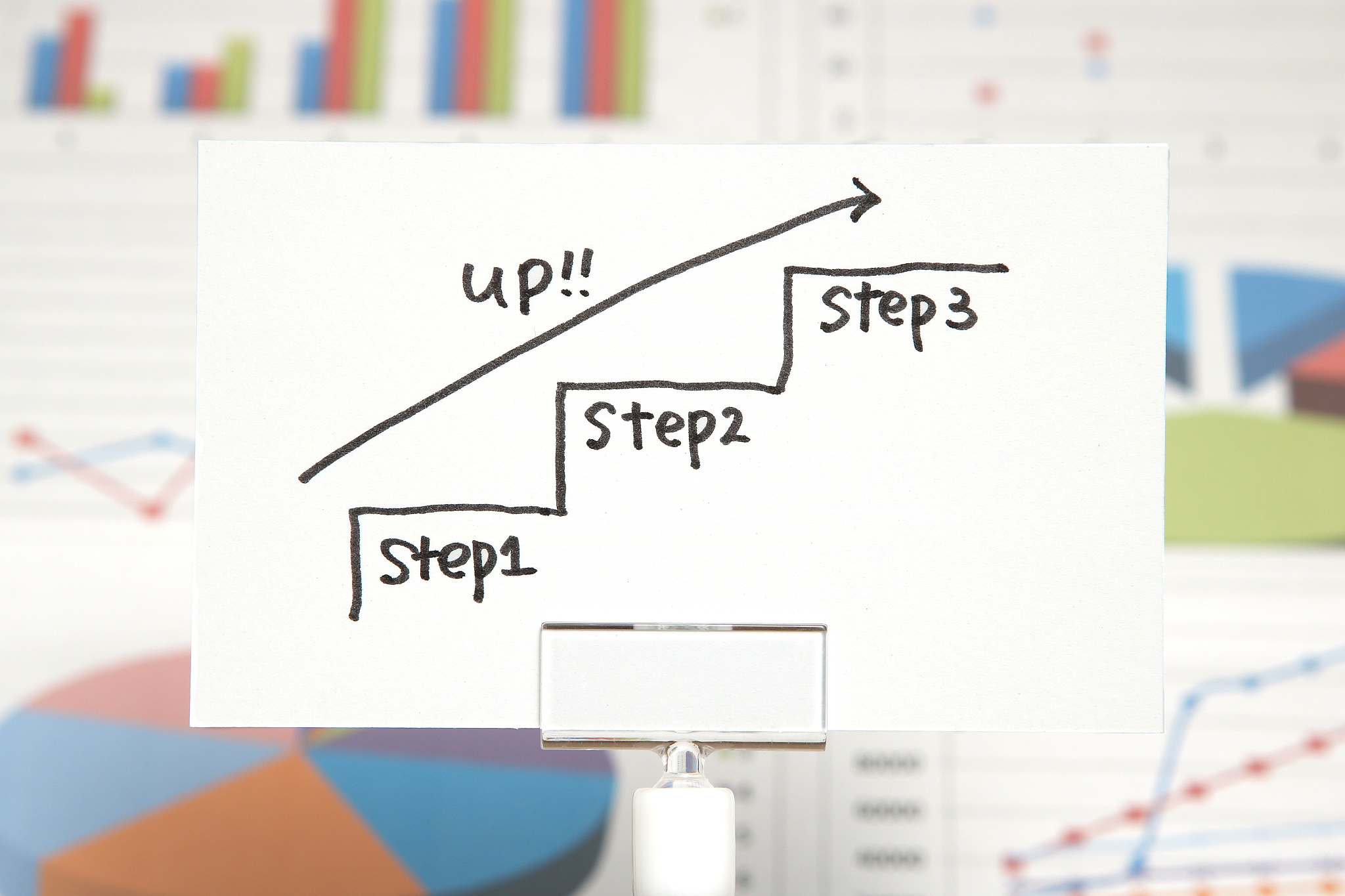 hand writing stairs heading upwards with arrow on paper.