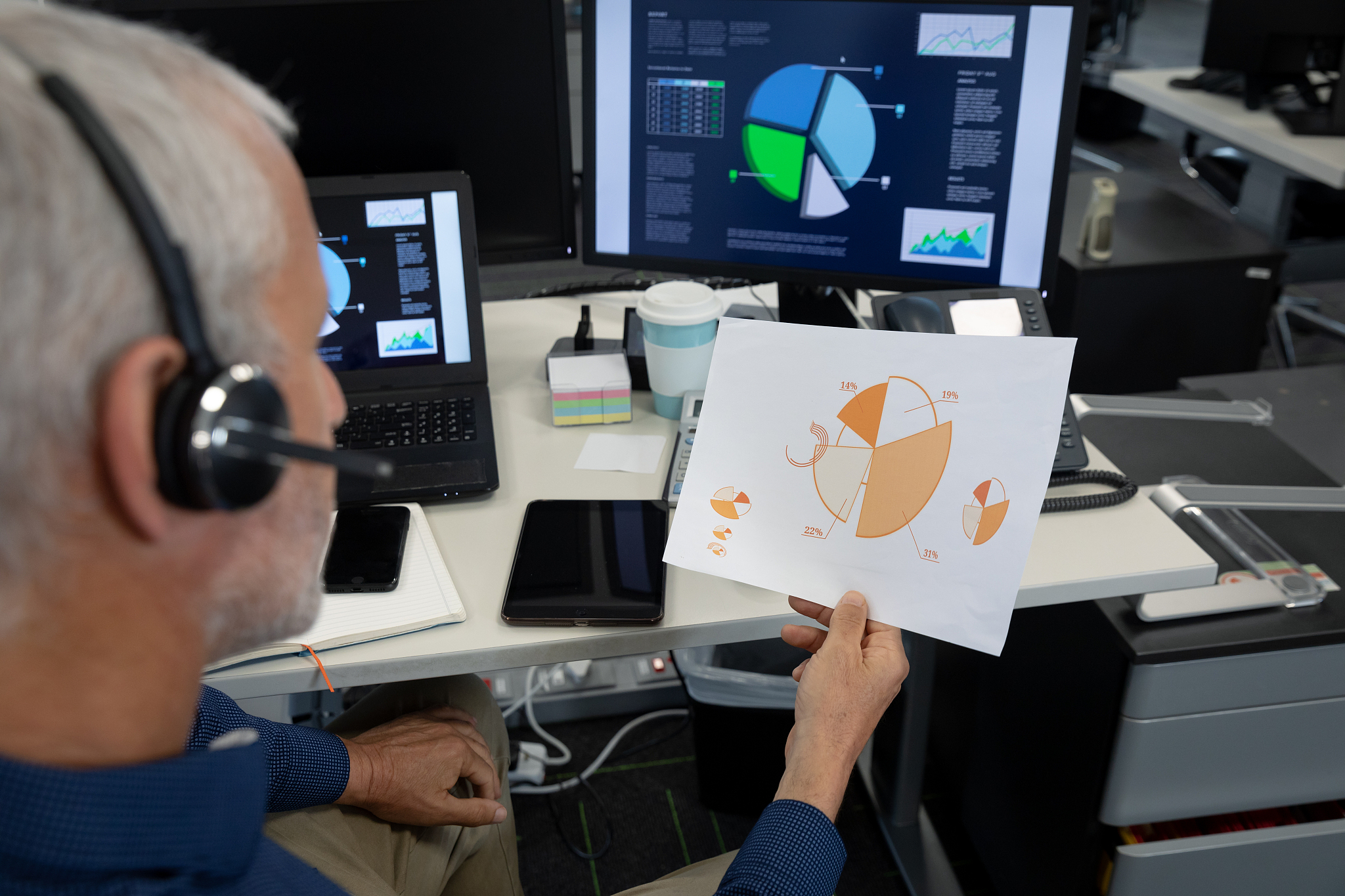 senior businessman wearing headset looking at document at modern