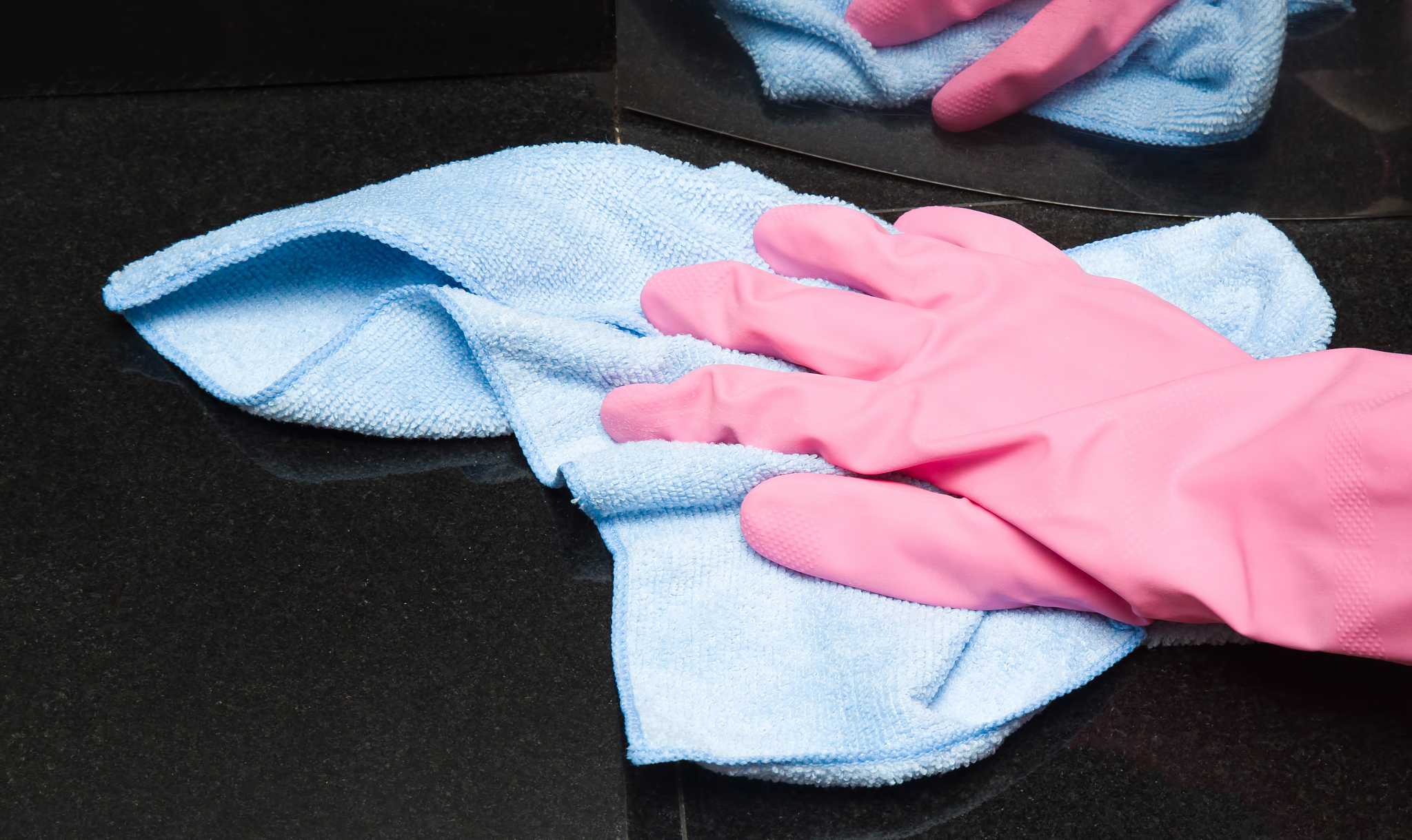 hand in glove wiping, washing and polishing marble surface.