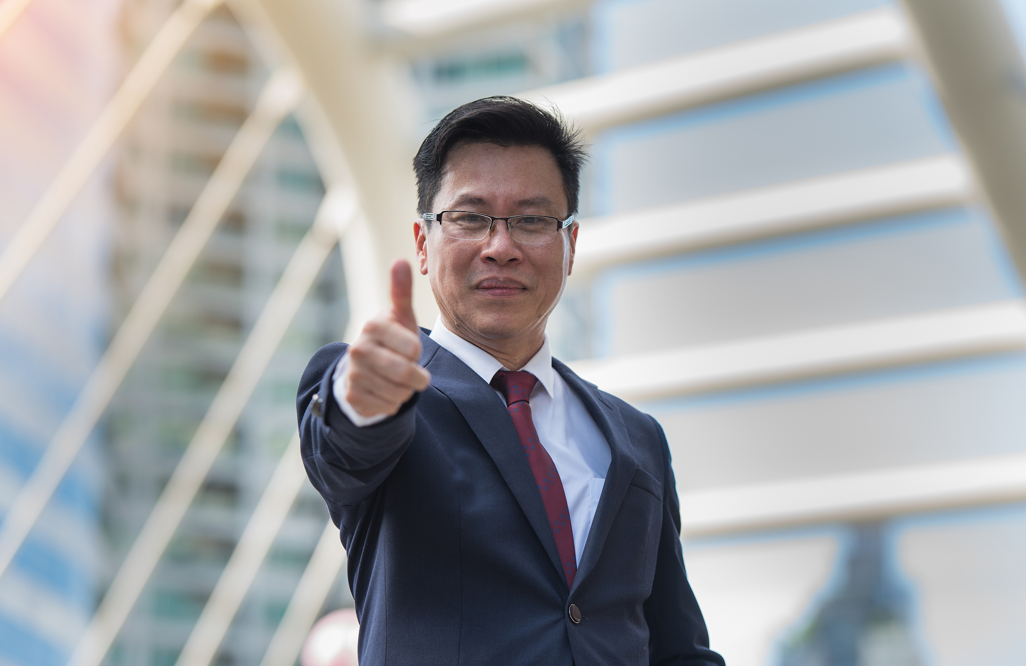 portrait of confident businessman showing thumbs up against buil