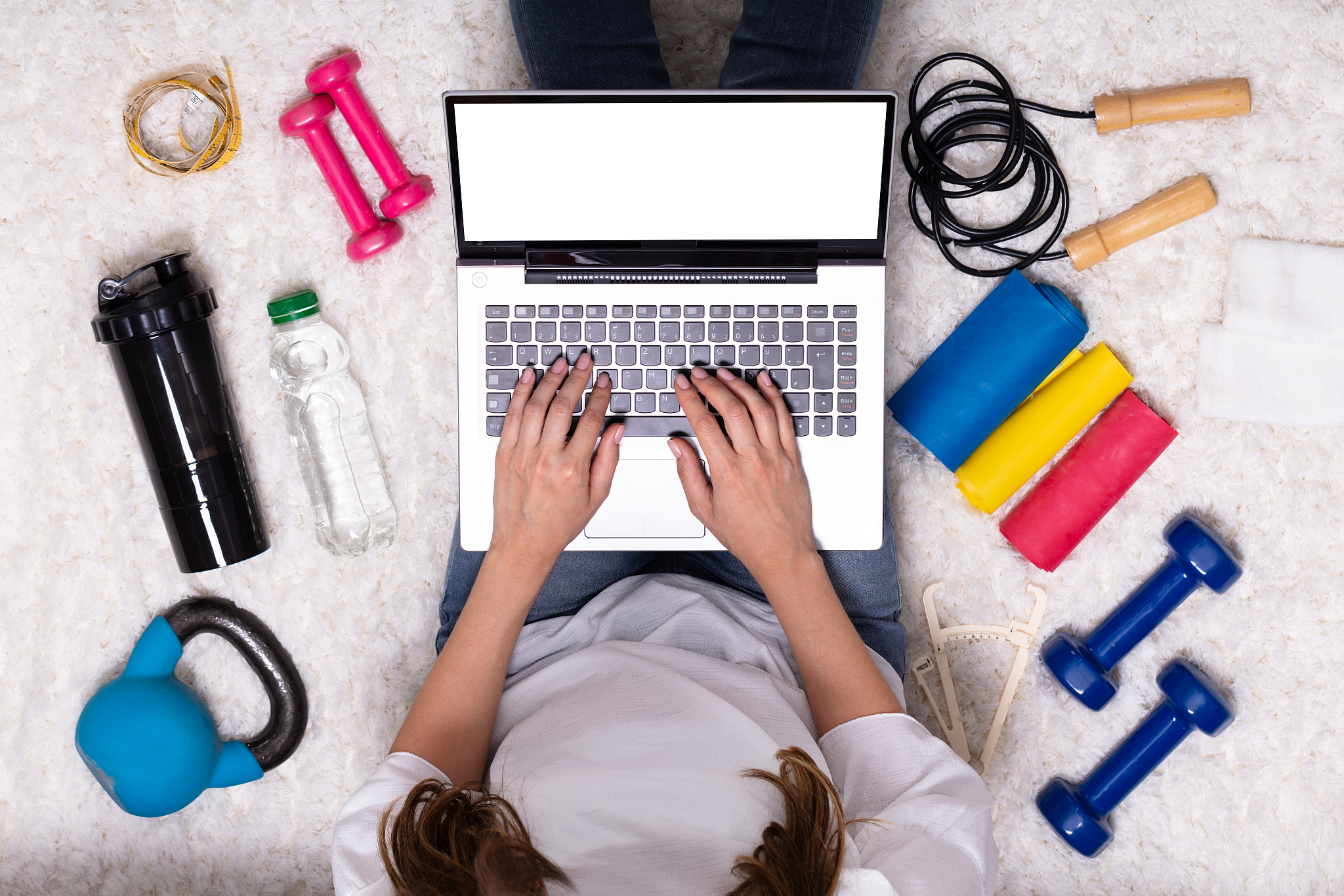 woman using laptop surrounded by fitness equipment