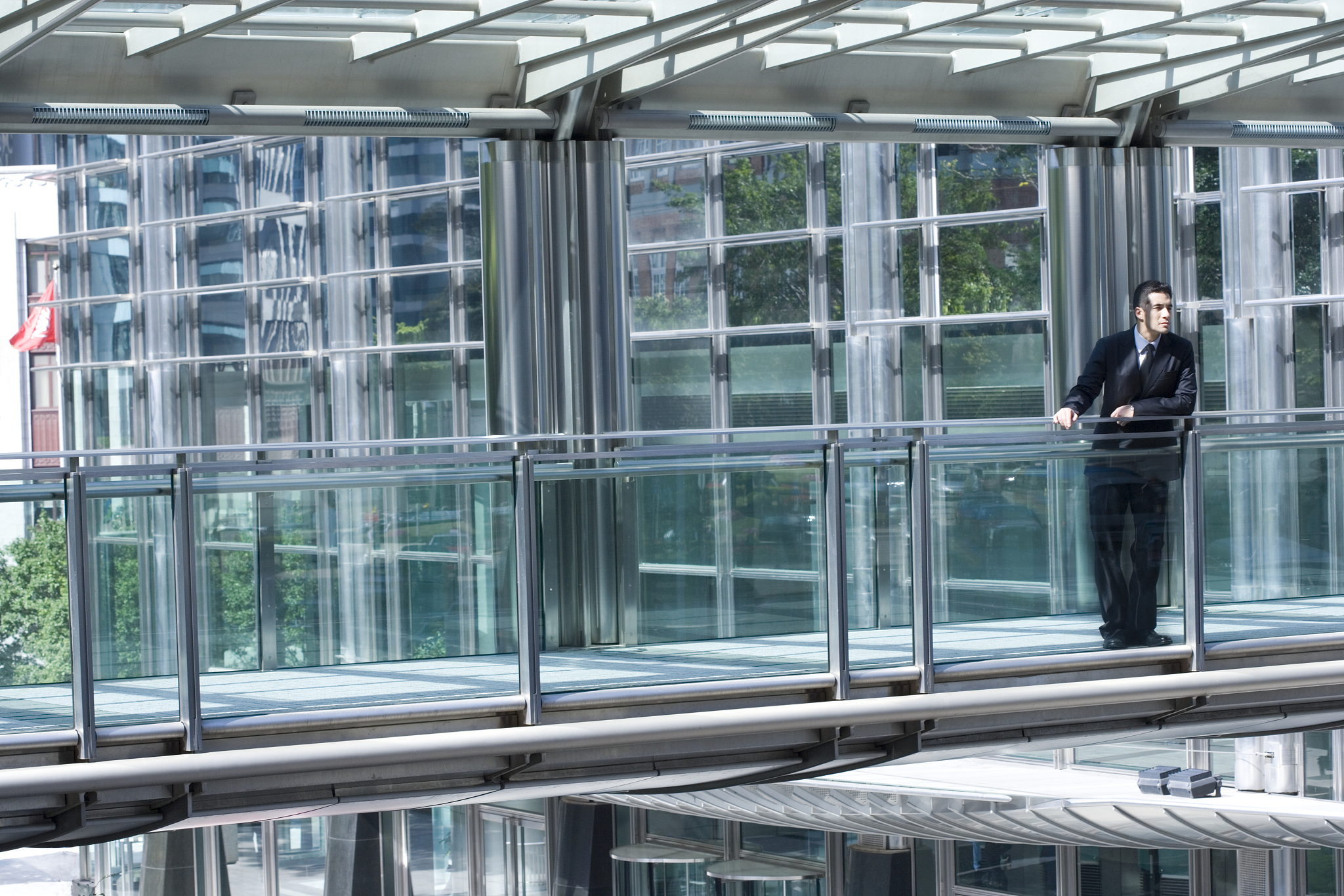 businessman leaning on railing in windowed building