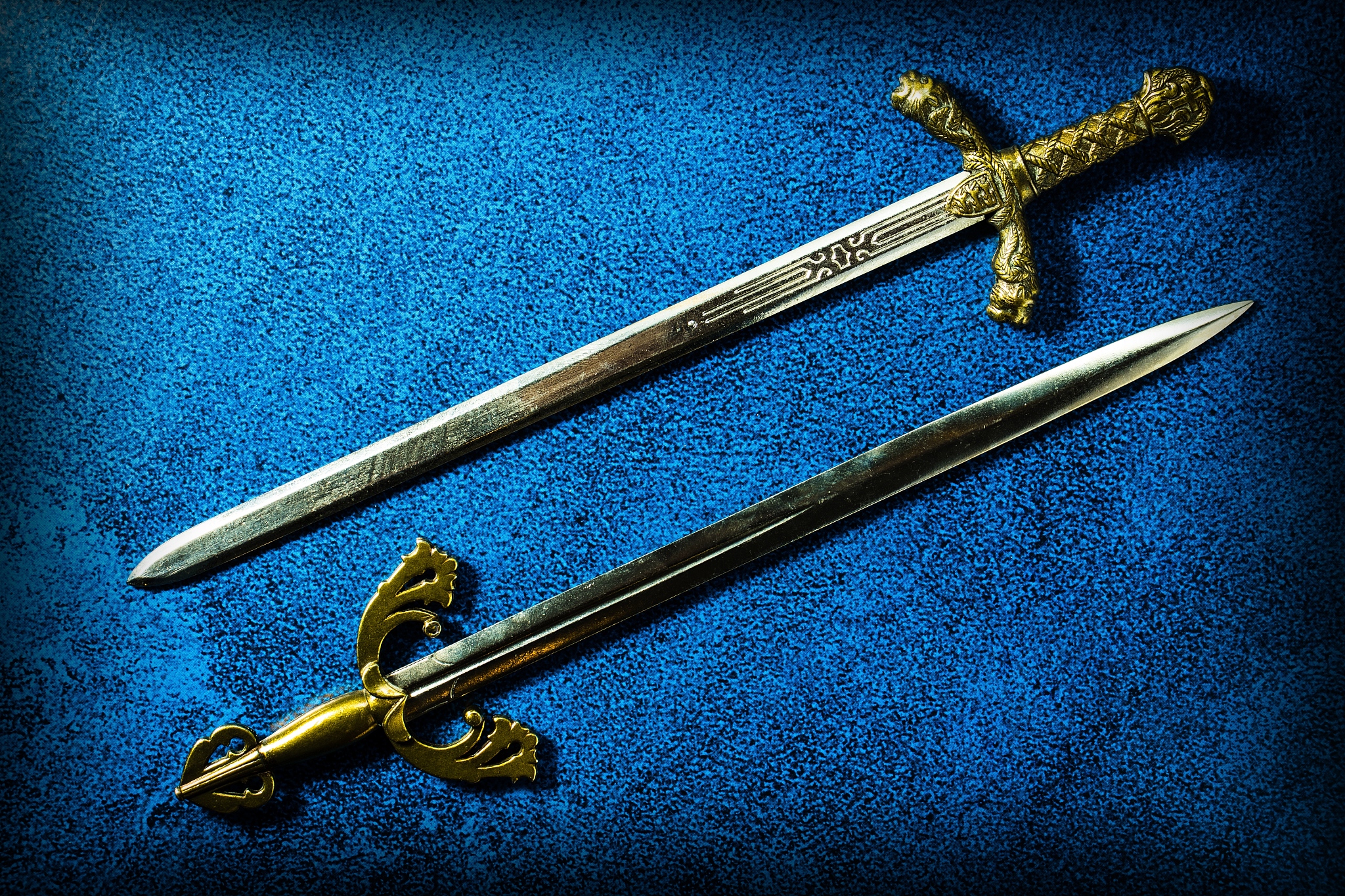 two knightly swords lie in parallel on a dark blue background. v