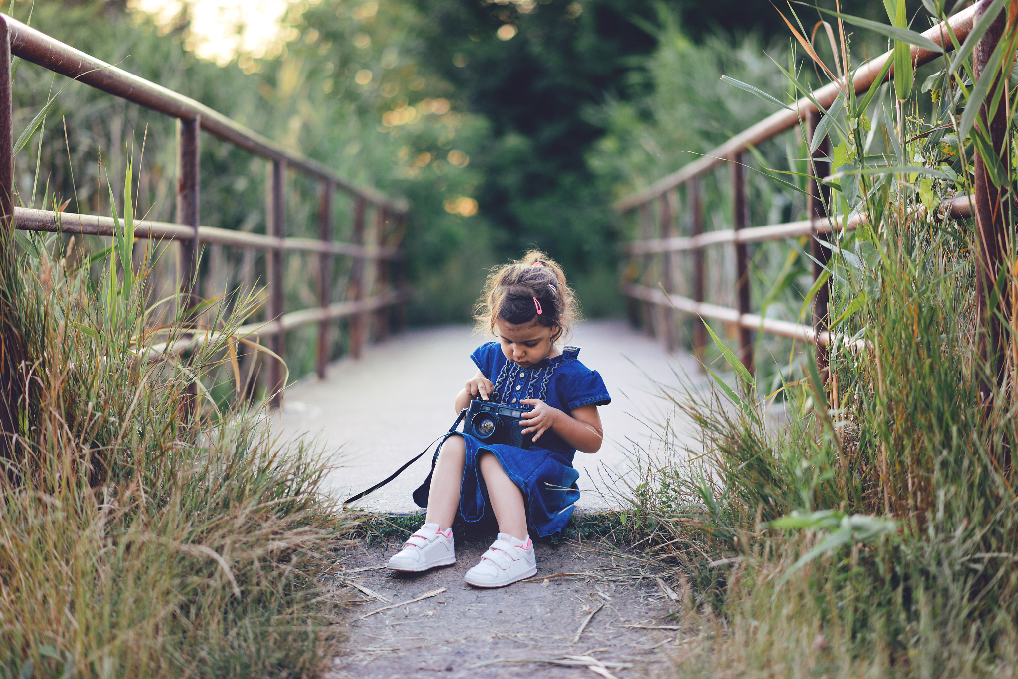 little girl playing with old camera