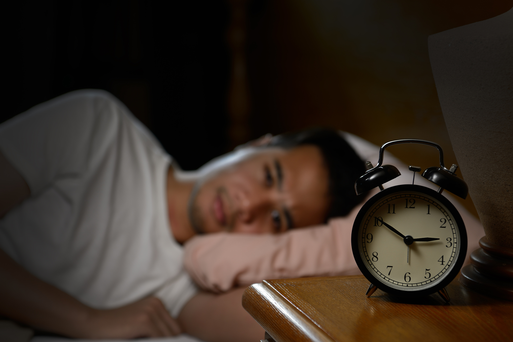 depressed man suffering from insomnia lying in bed