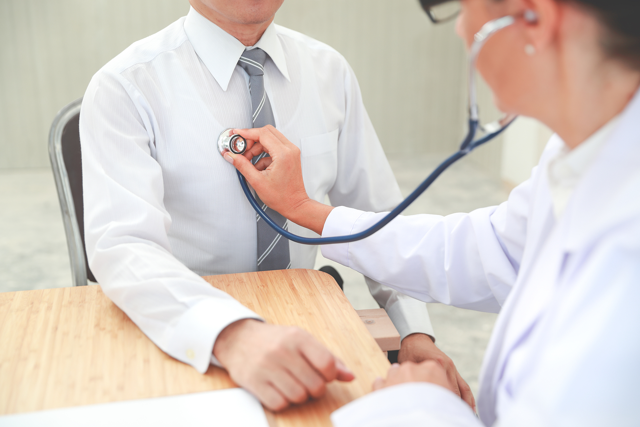 doctor checking male patient heart beat