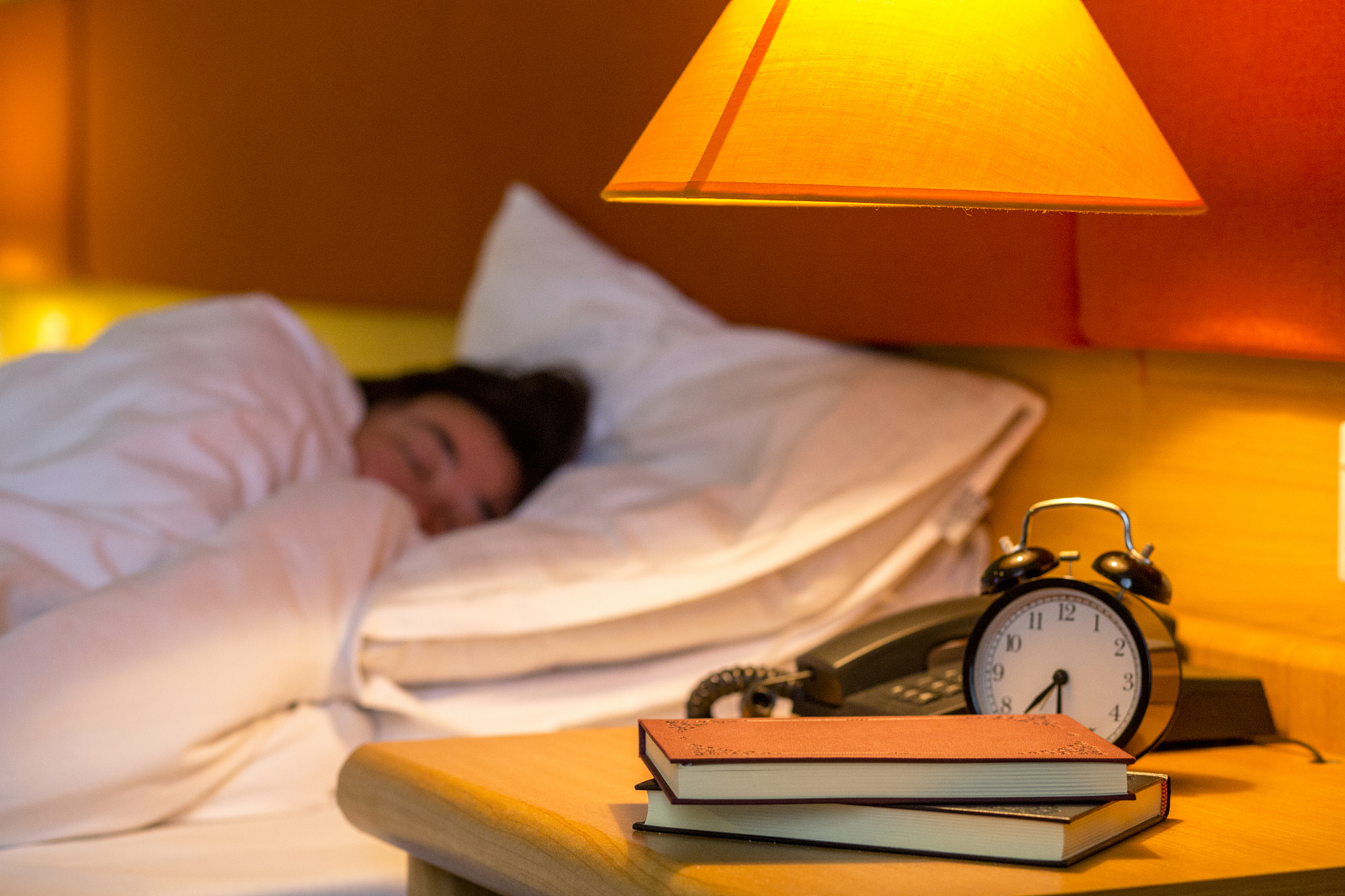 book and alarm clock at bedside, sleeping on bed