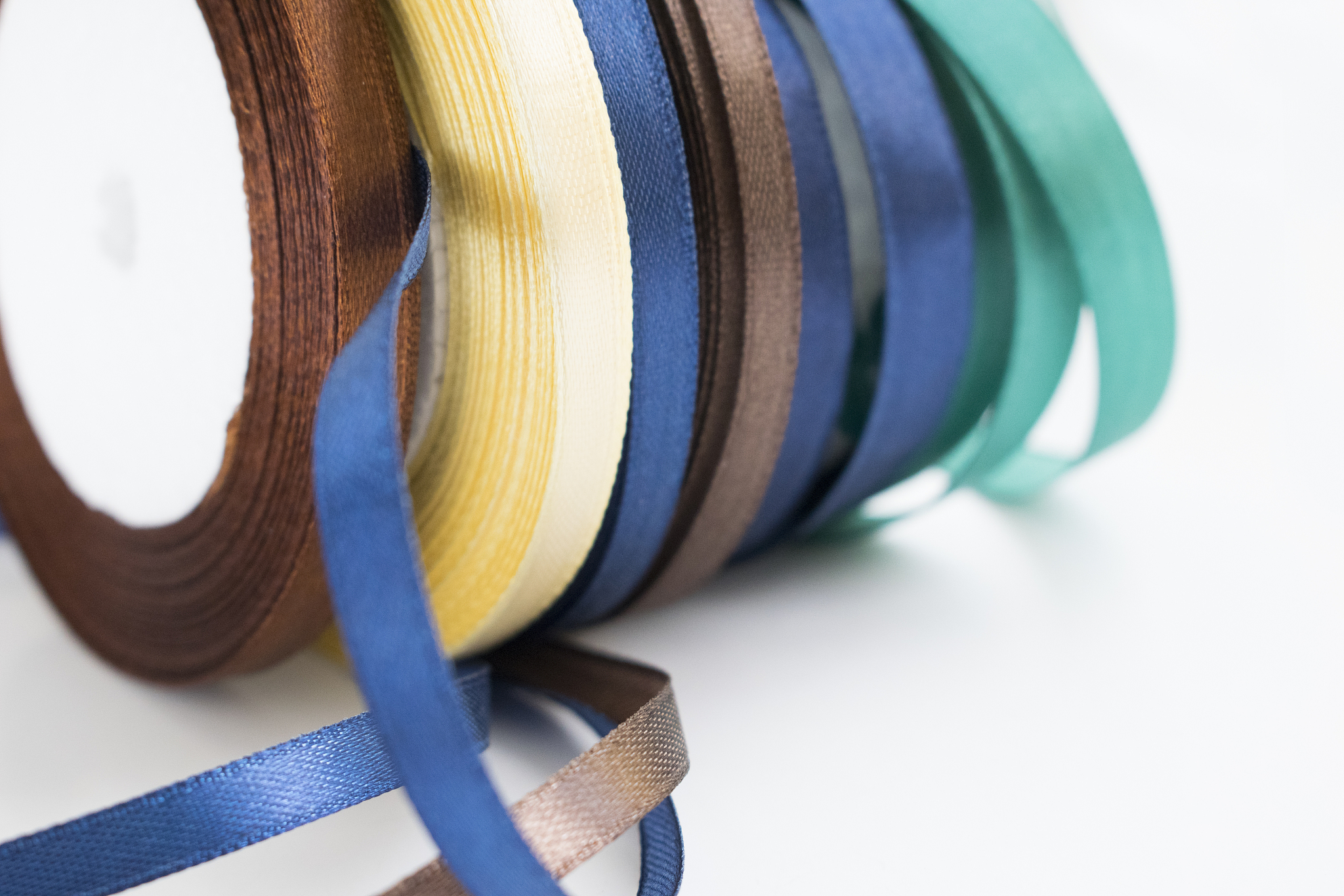 stack of satin ribbon coils. blue, green, brown and yellow ribbo