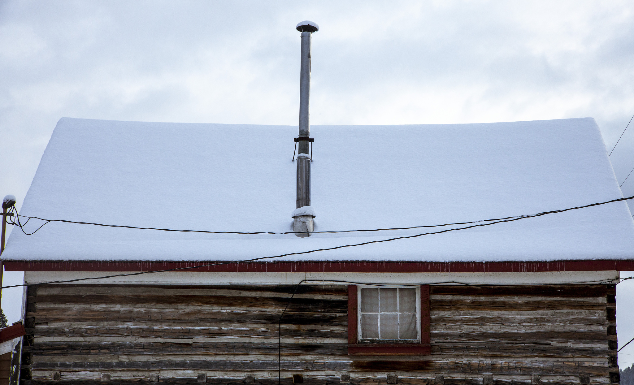 snowy log cabin rooftop with exhaust pipe