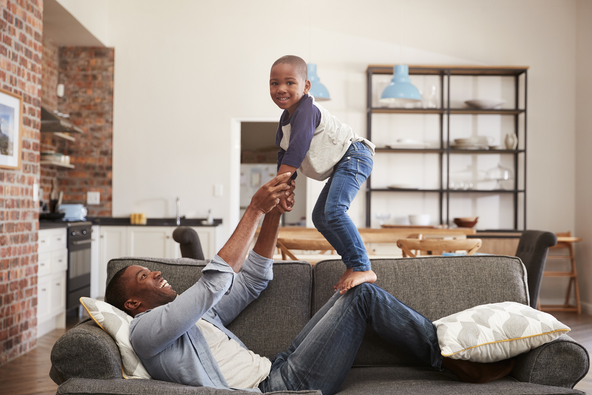 father and son having fun playing on sofa together