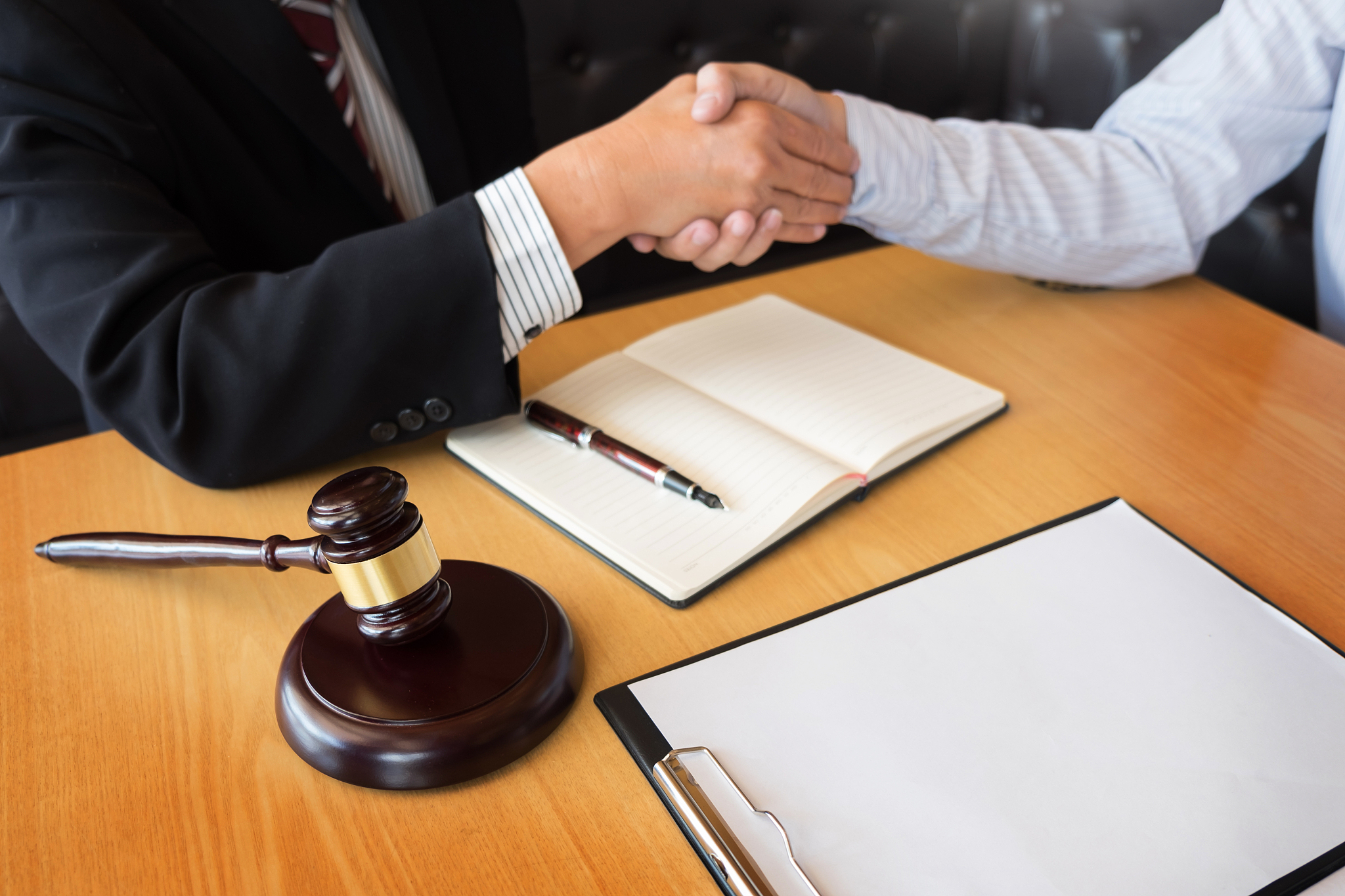 cropped hand of man shaking hands with male lawyer at desk