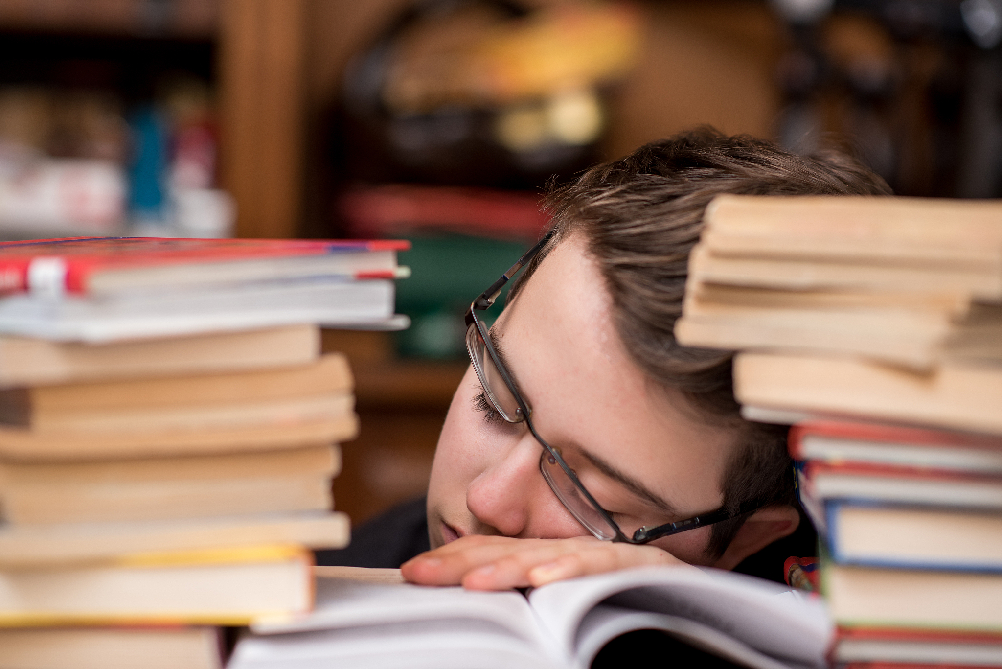 tired child sleeping while studying. boy with glasses studying a