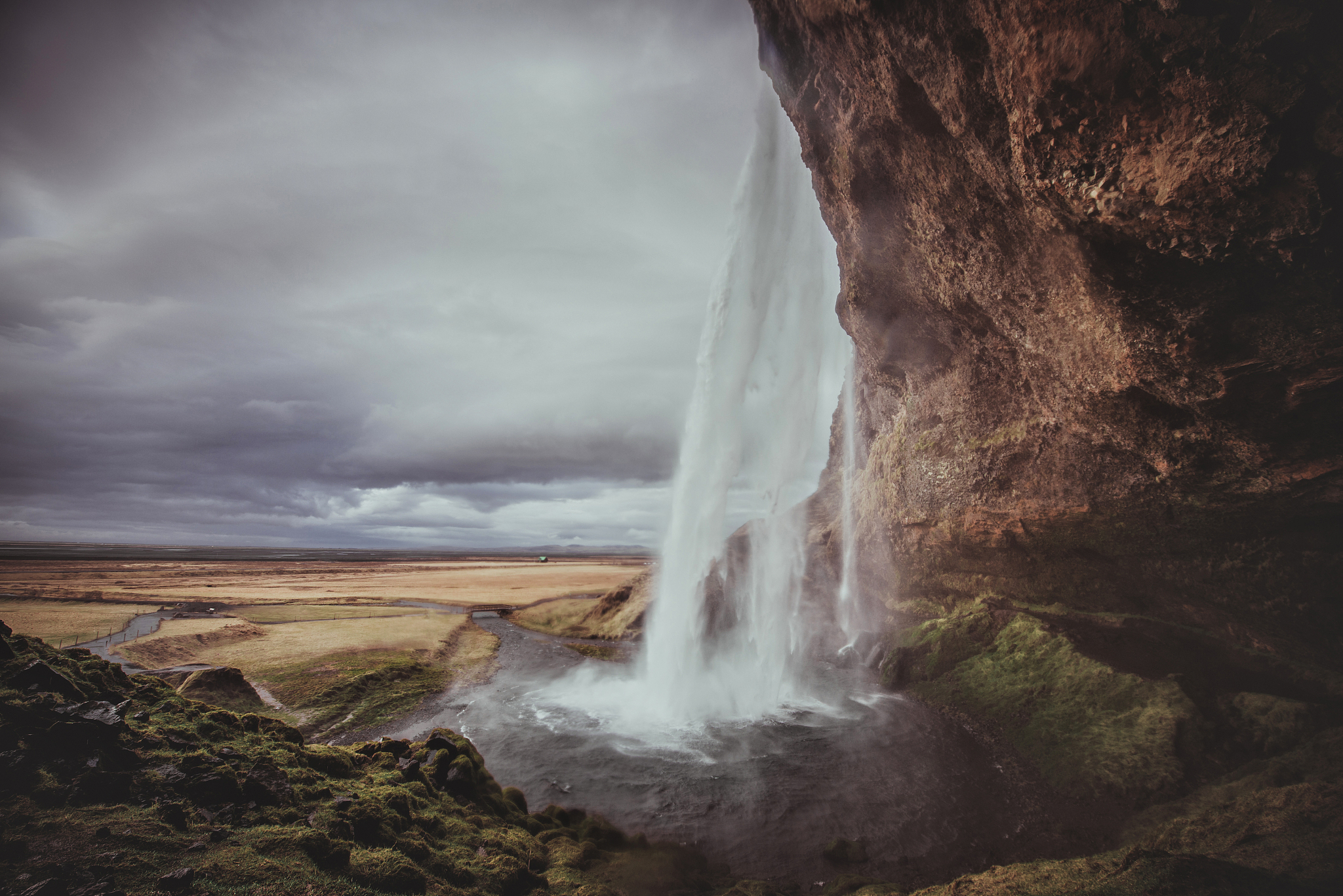 landscape with view of waterfall from below under overcast sky, 