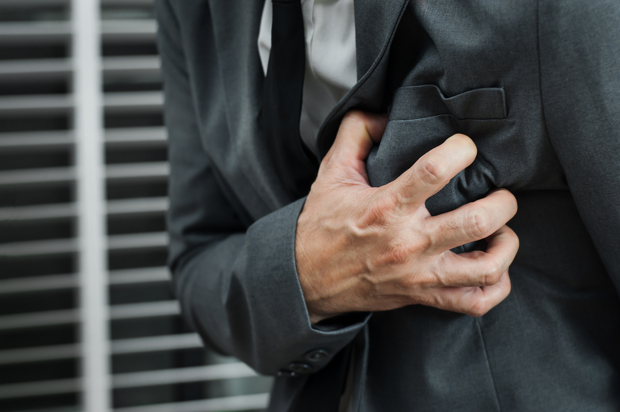 close up businessman in grey suit has heart attack. exhausted, i
