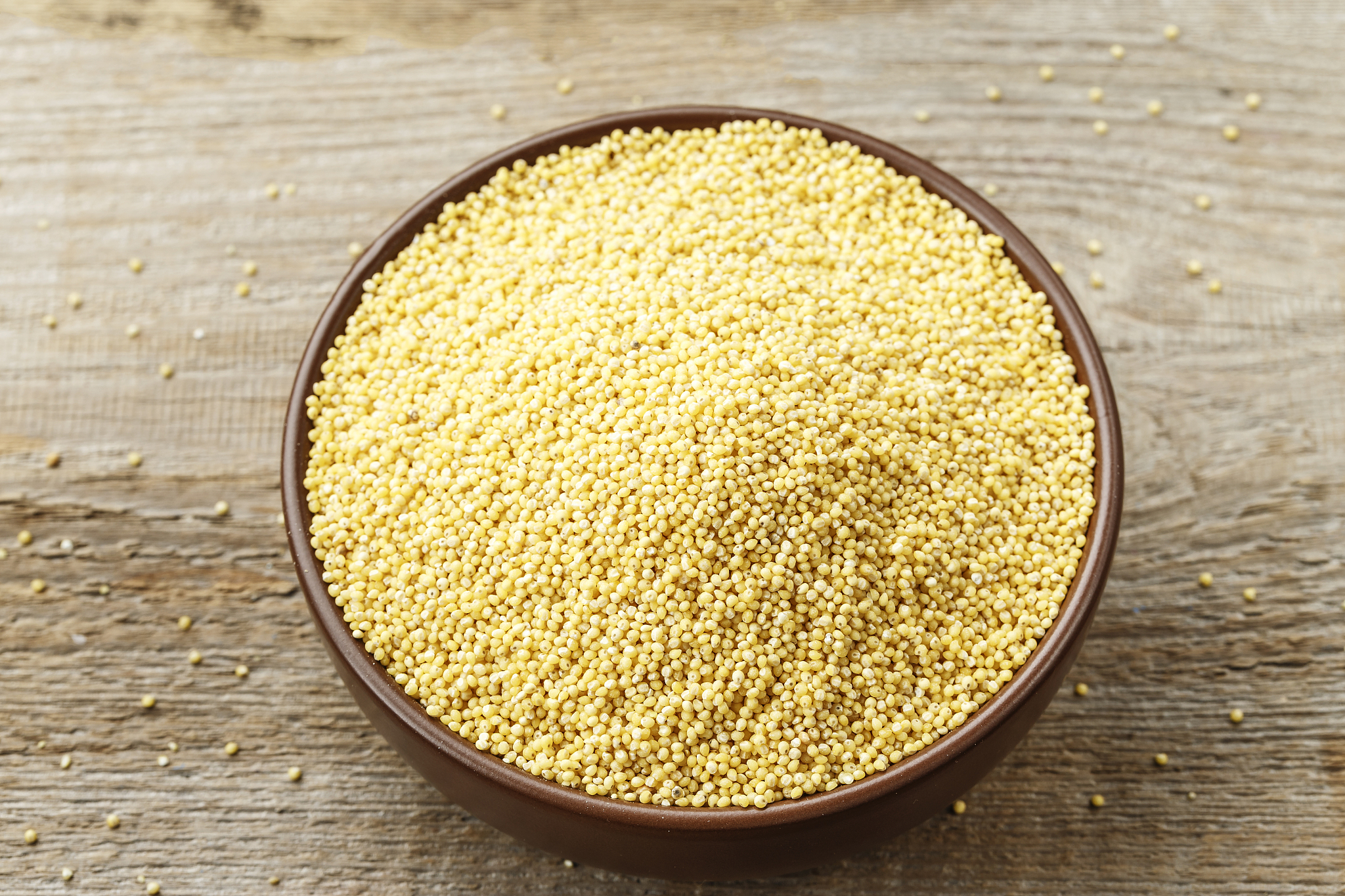 plate with raw cereal millet on a wooden background.
