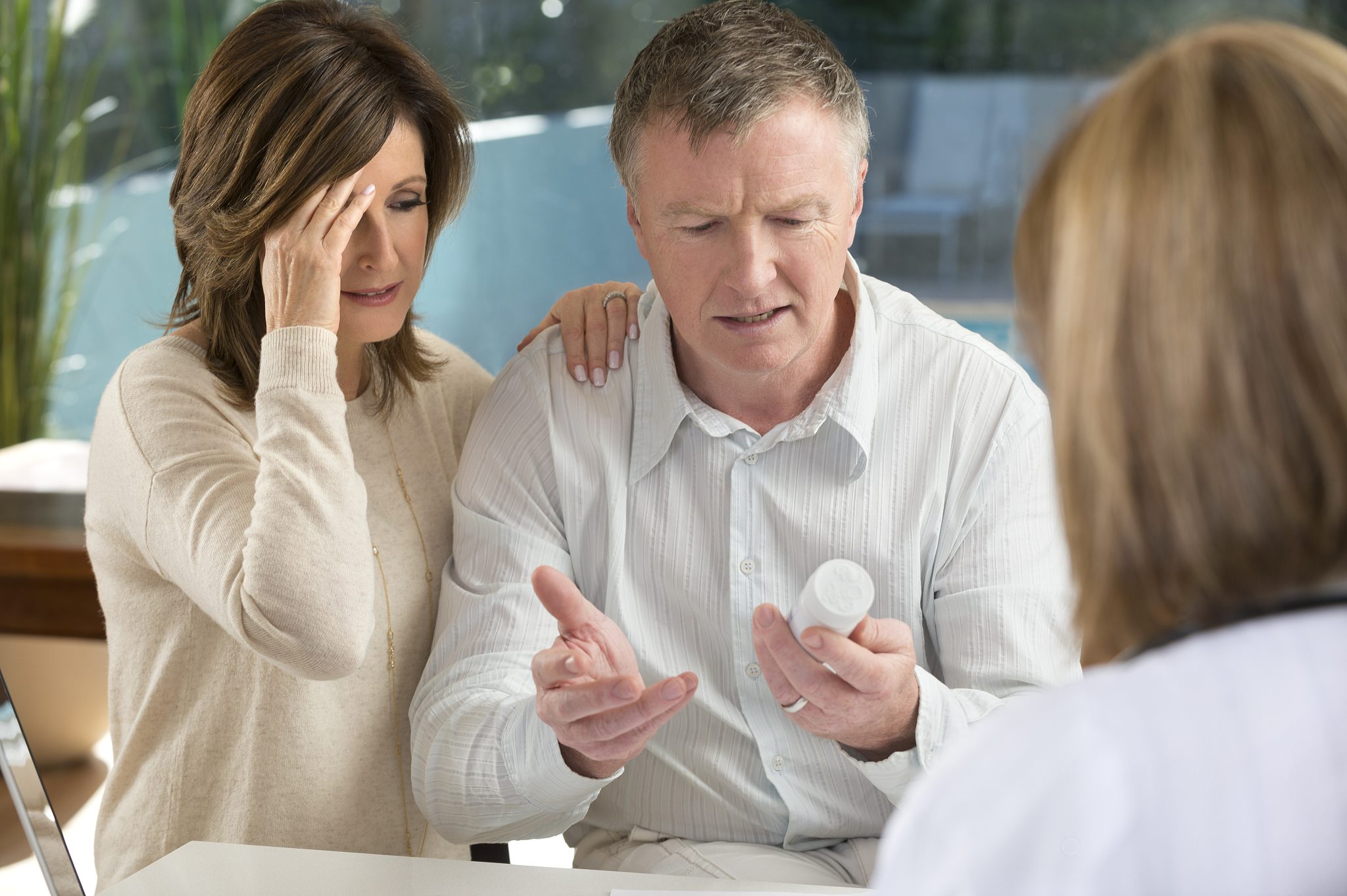 upset mature couple with doctor and medicine