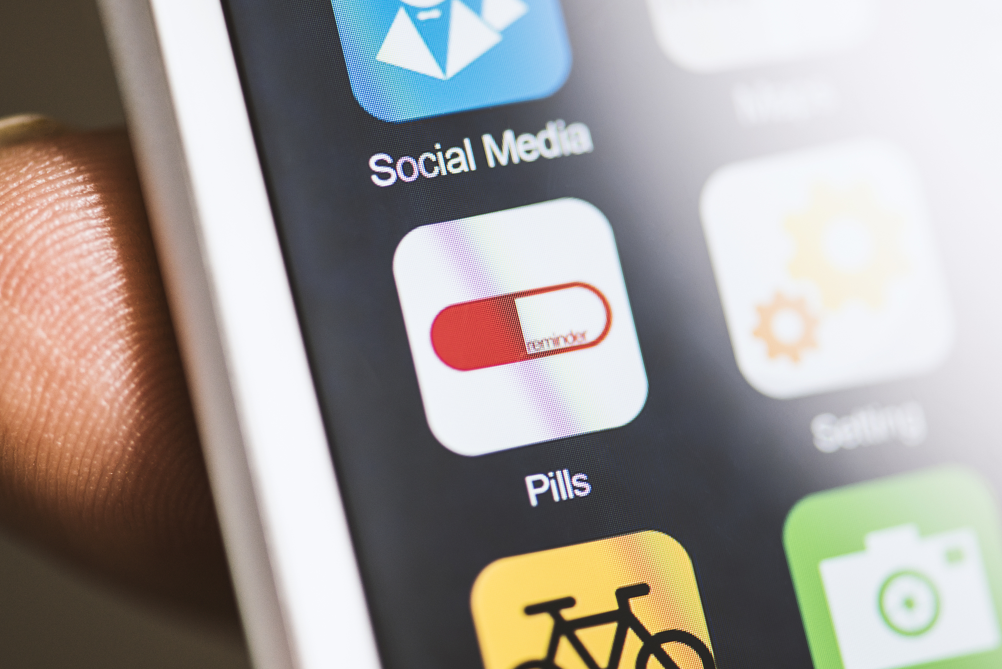 hand holding phone, pill reminder app on screen