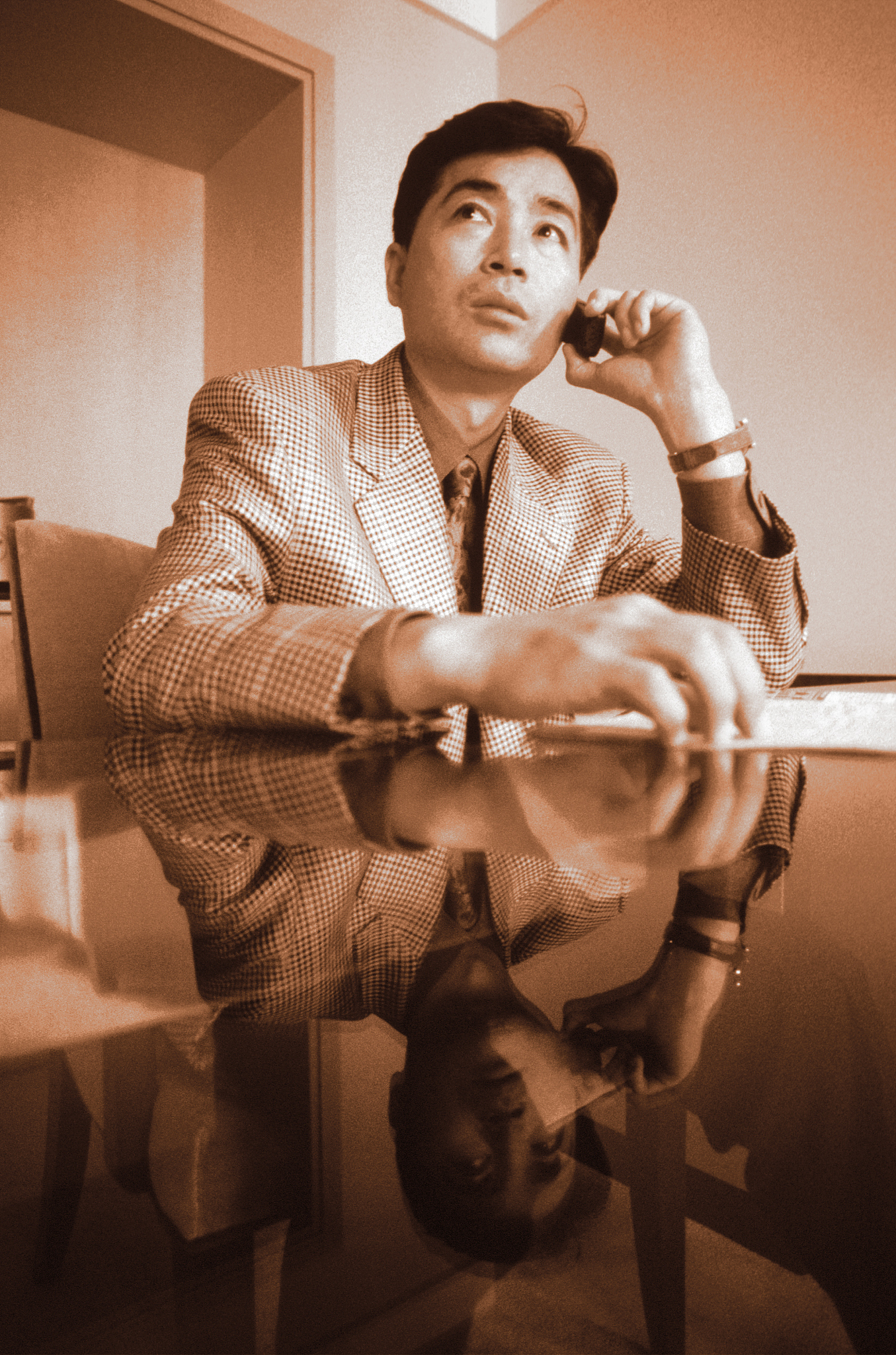 businessman sitting at desk using mobile phone (b&w)
