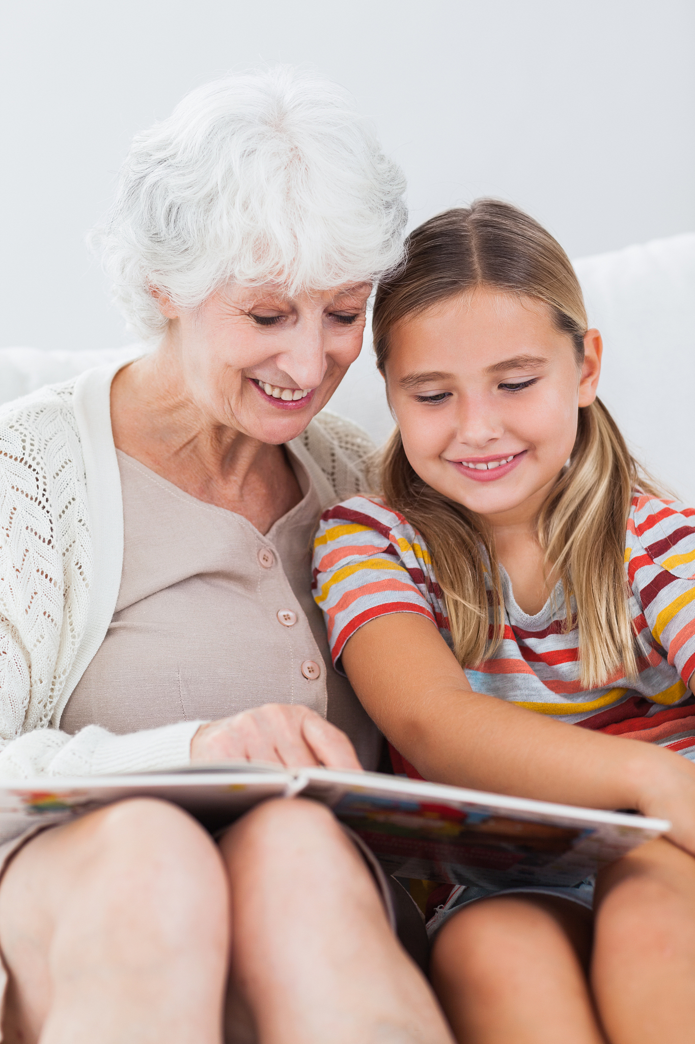 little girl sitting on couch reading with granny