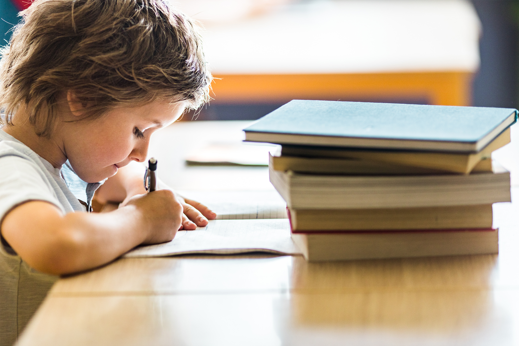 profile view of schoolboy writing on a class at school.