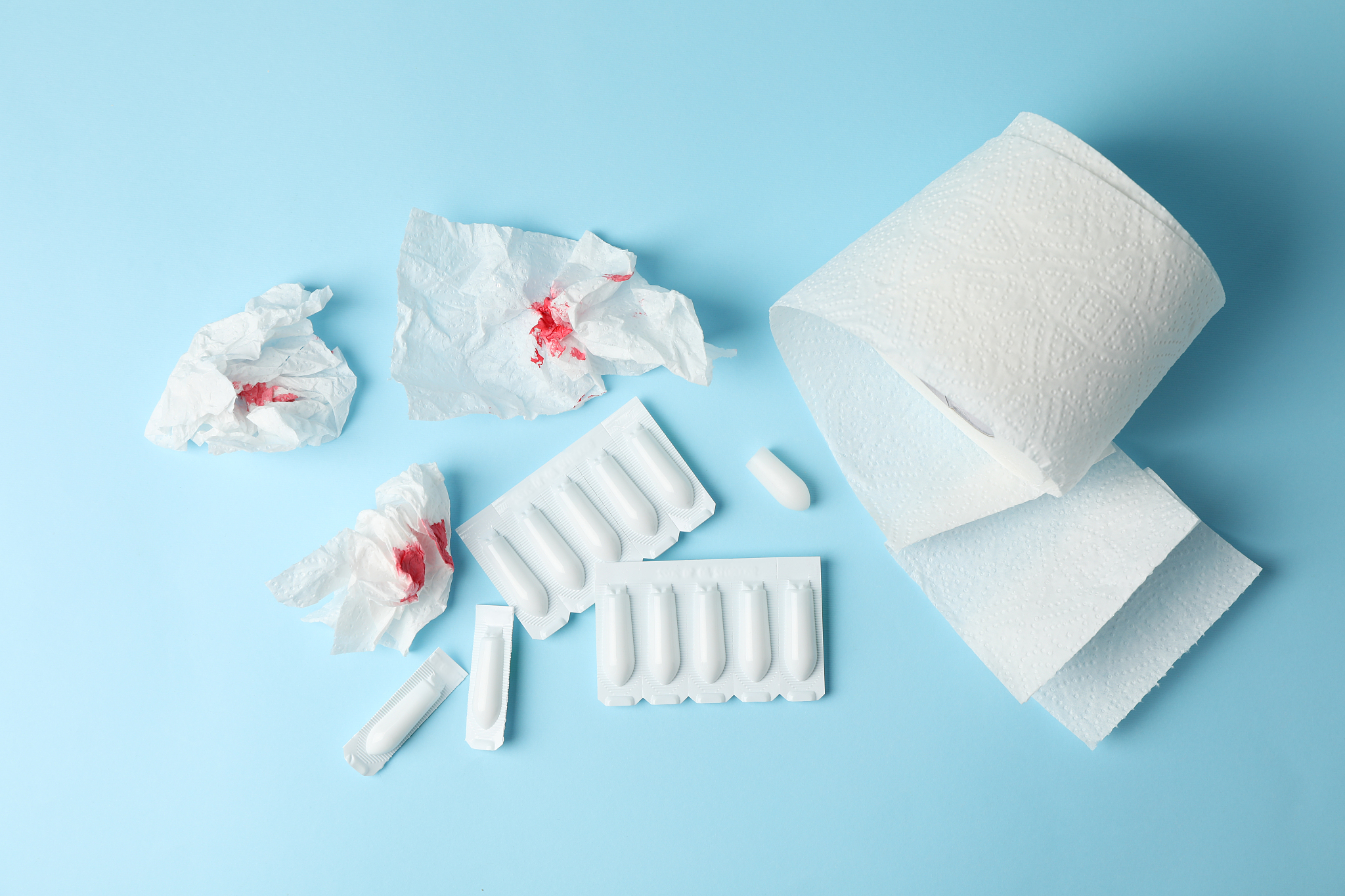 toilet paper, candles and paper with blood on blue background, t