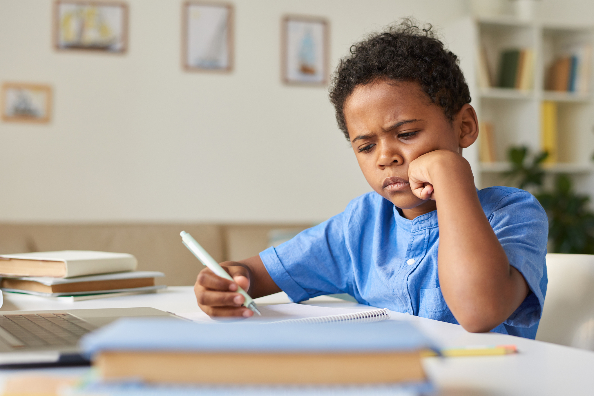 concentrated african-american schoolboy in blue shirt sitting at