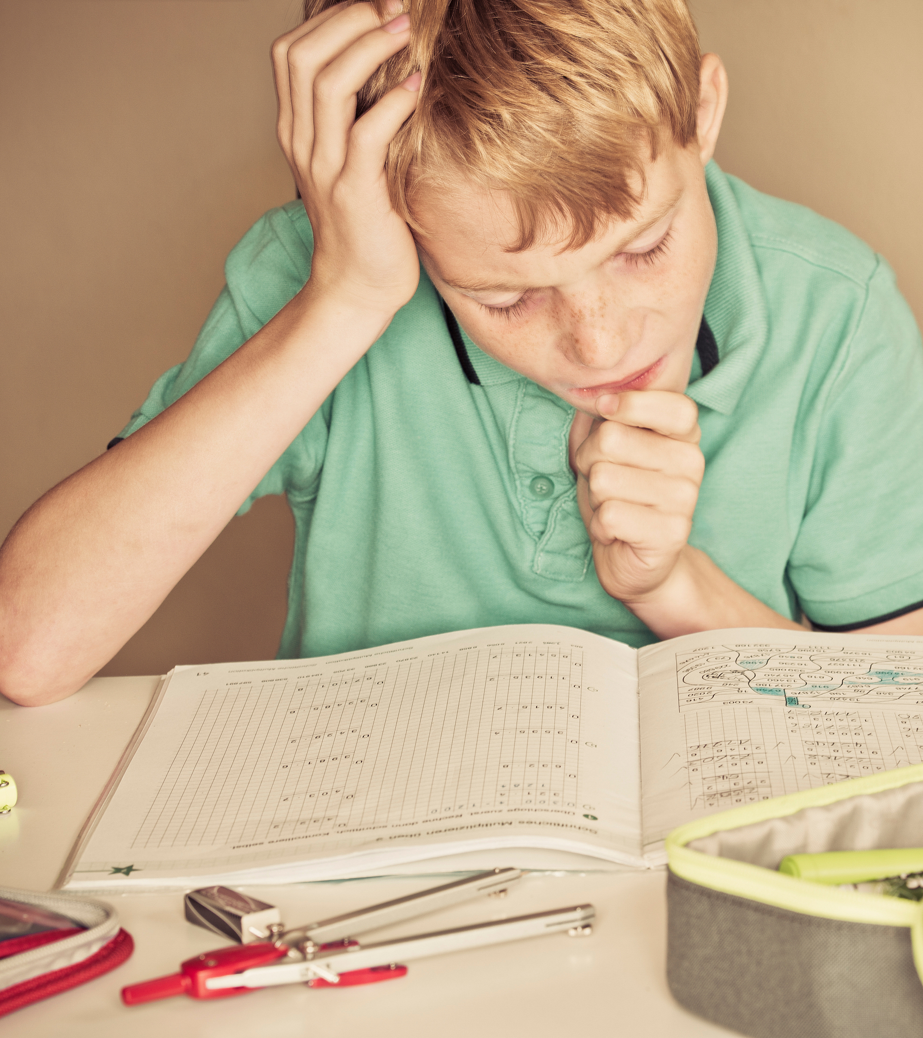 close-up of thoughtful boy studying at table against wall