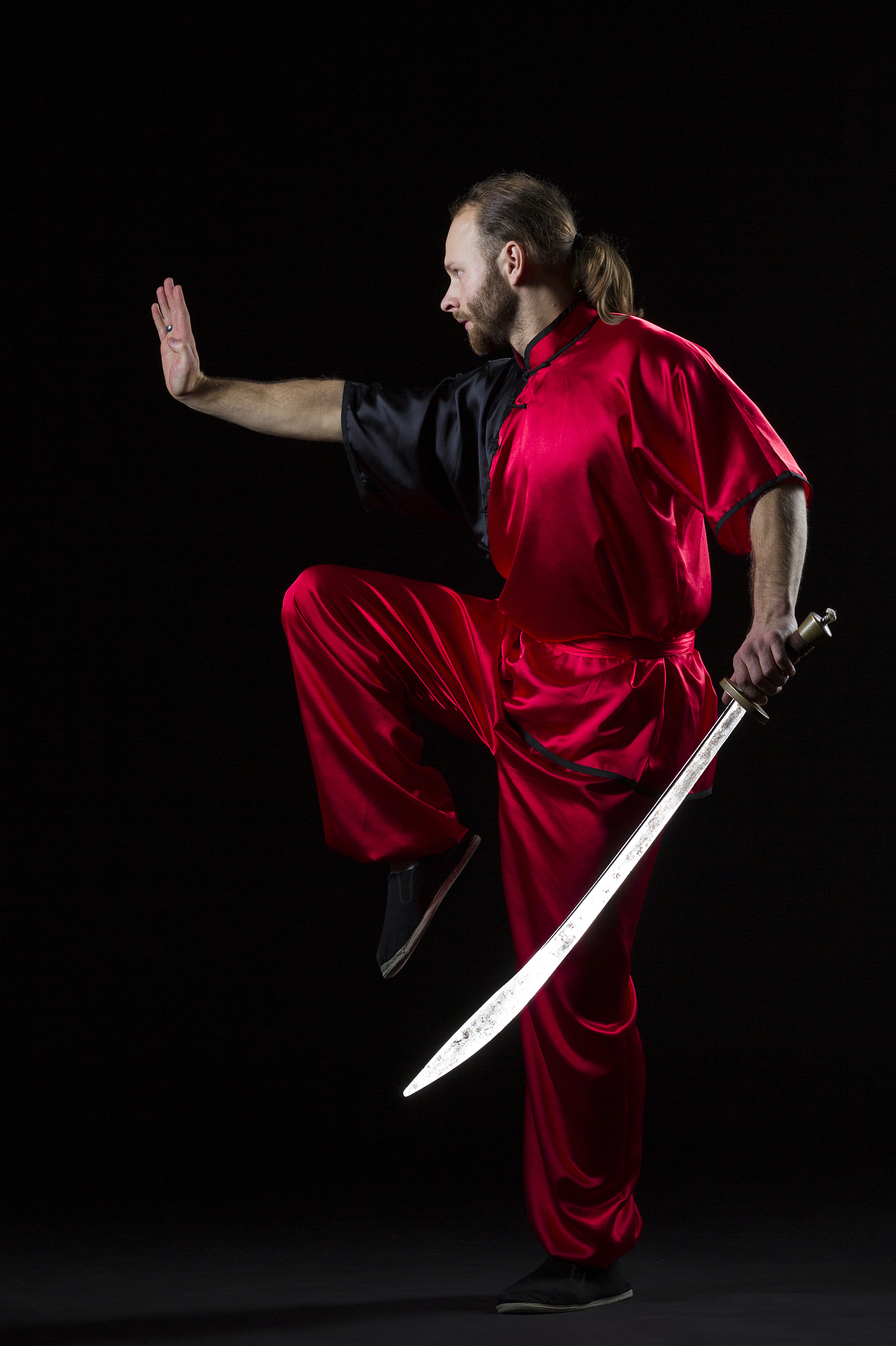 shaolin kung fu fighting position with dao sword on black