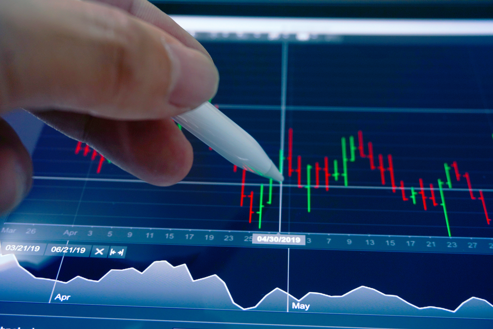 trader 's hand point pen on chart trading screen.