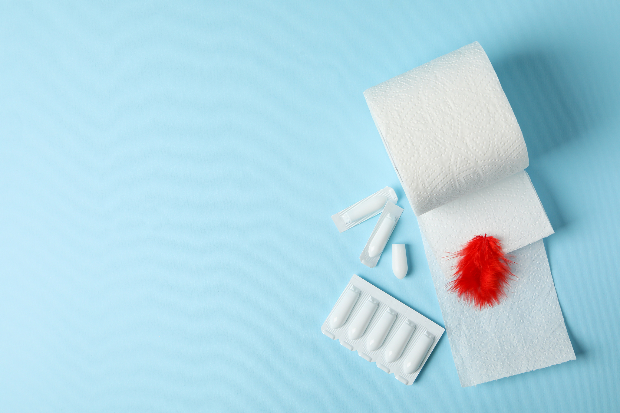 toilet paper, feather and candles on blue background. hemorrhoid