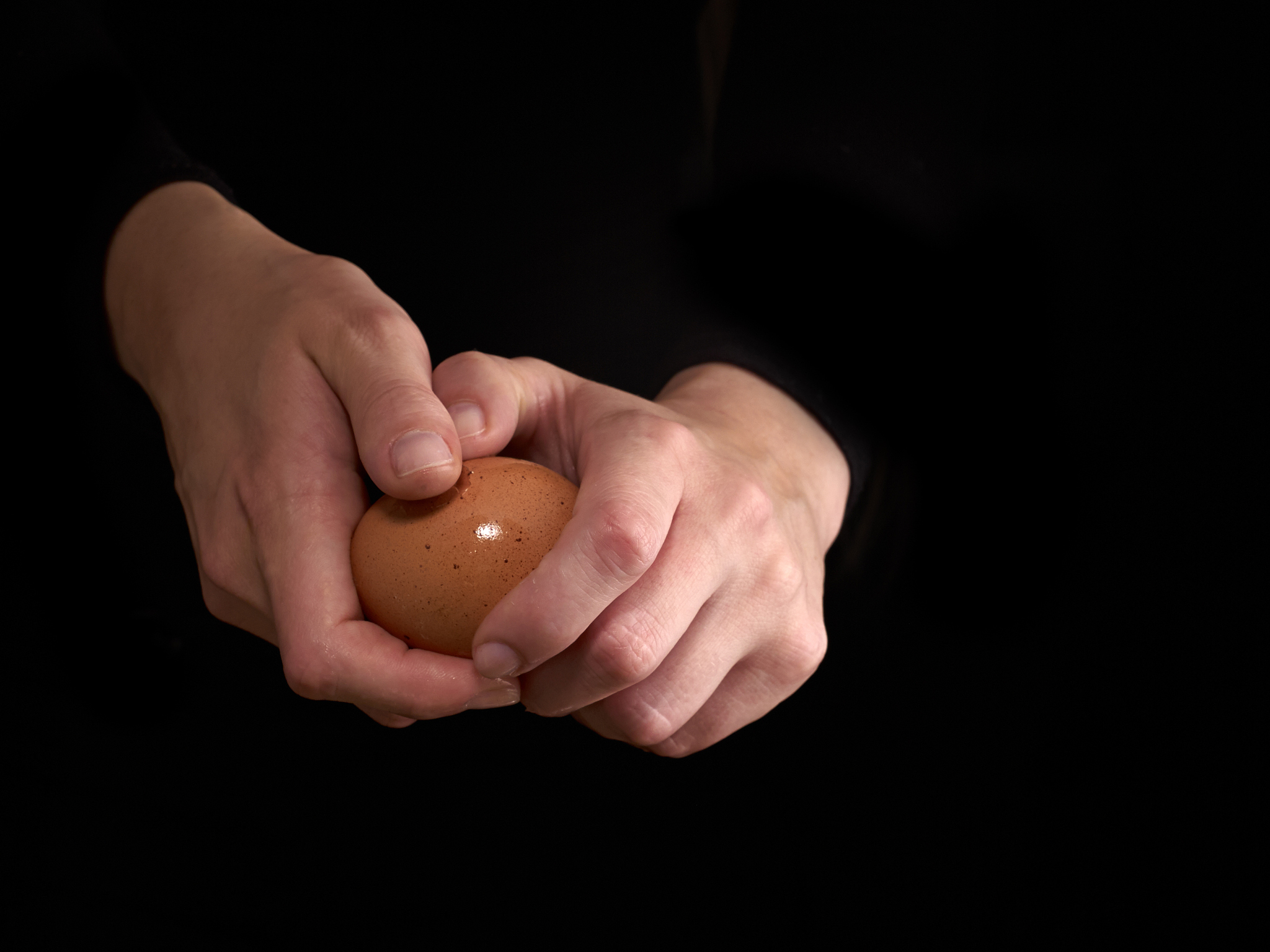 hands breaking an egg.