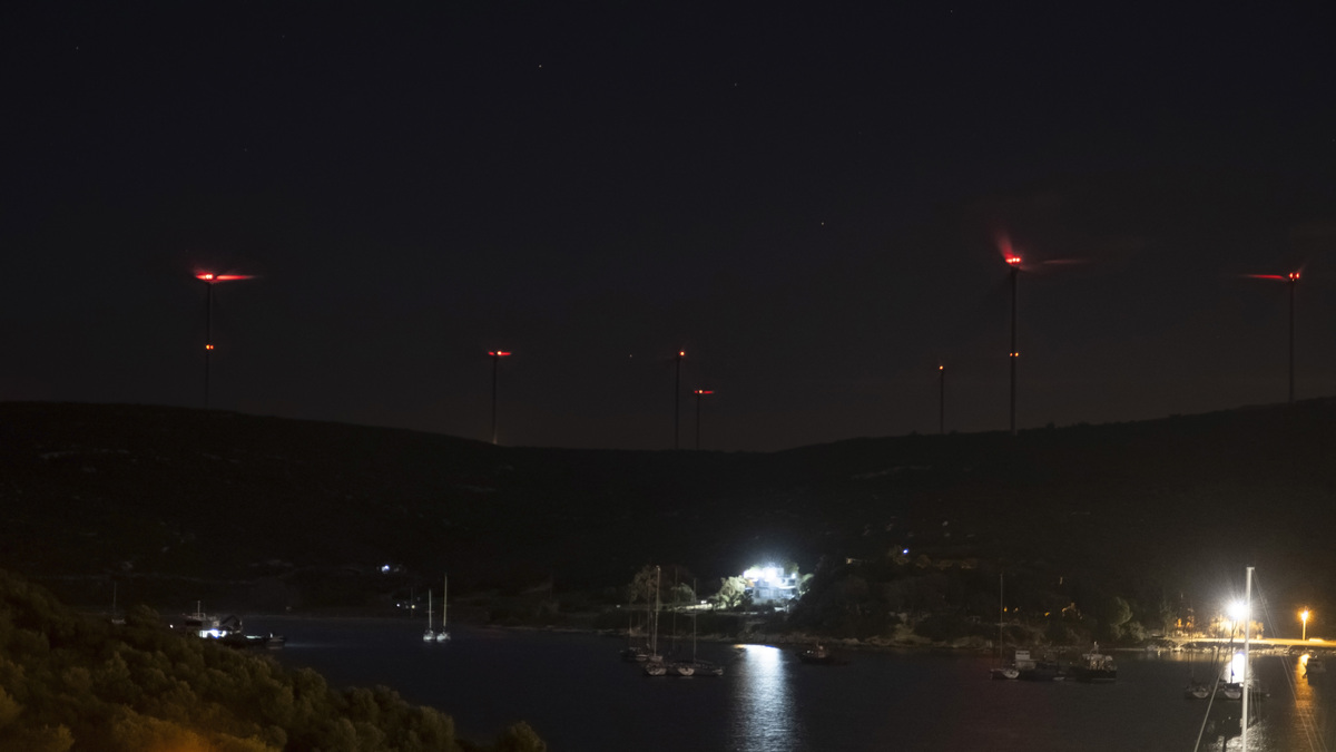 夜晚灯火辉煌的港口,山丘上的风力涡轮机闪闪发光,在