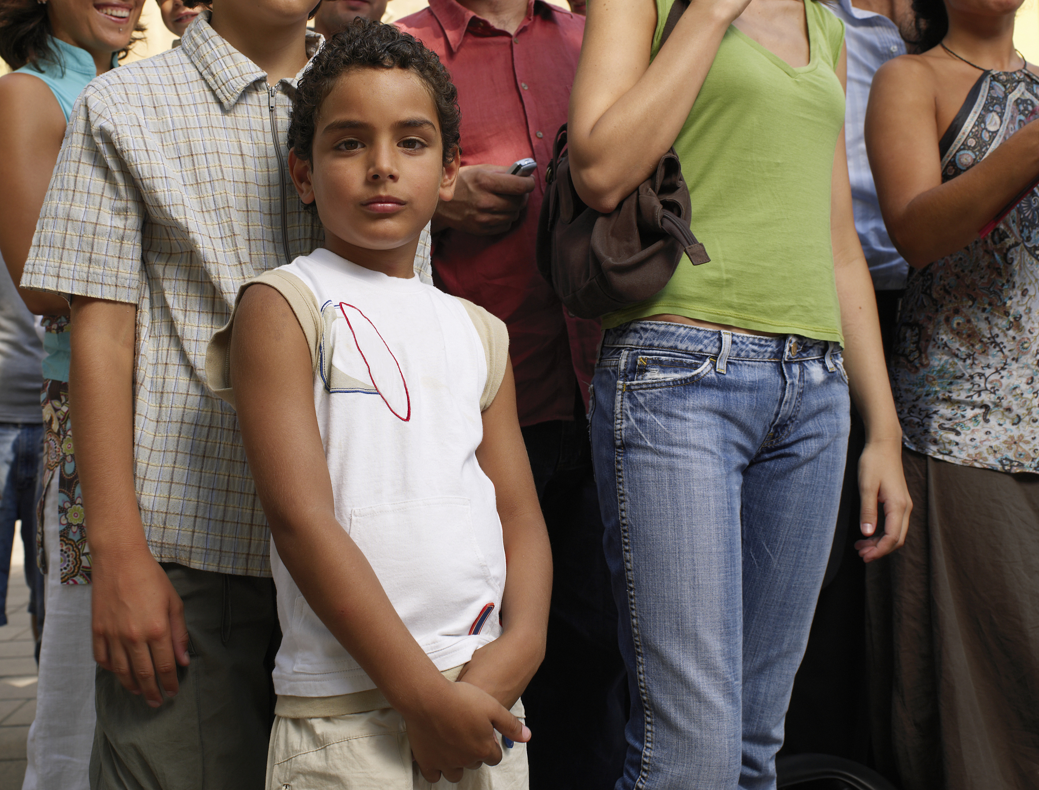 boy (5-7) standing amongst crowd, smiling, portrait