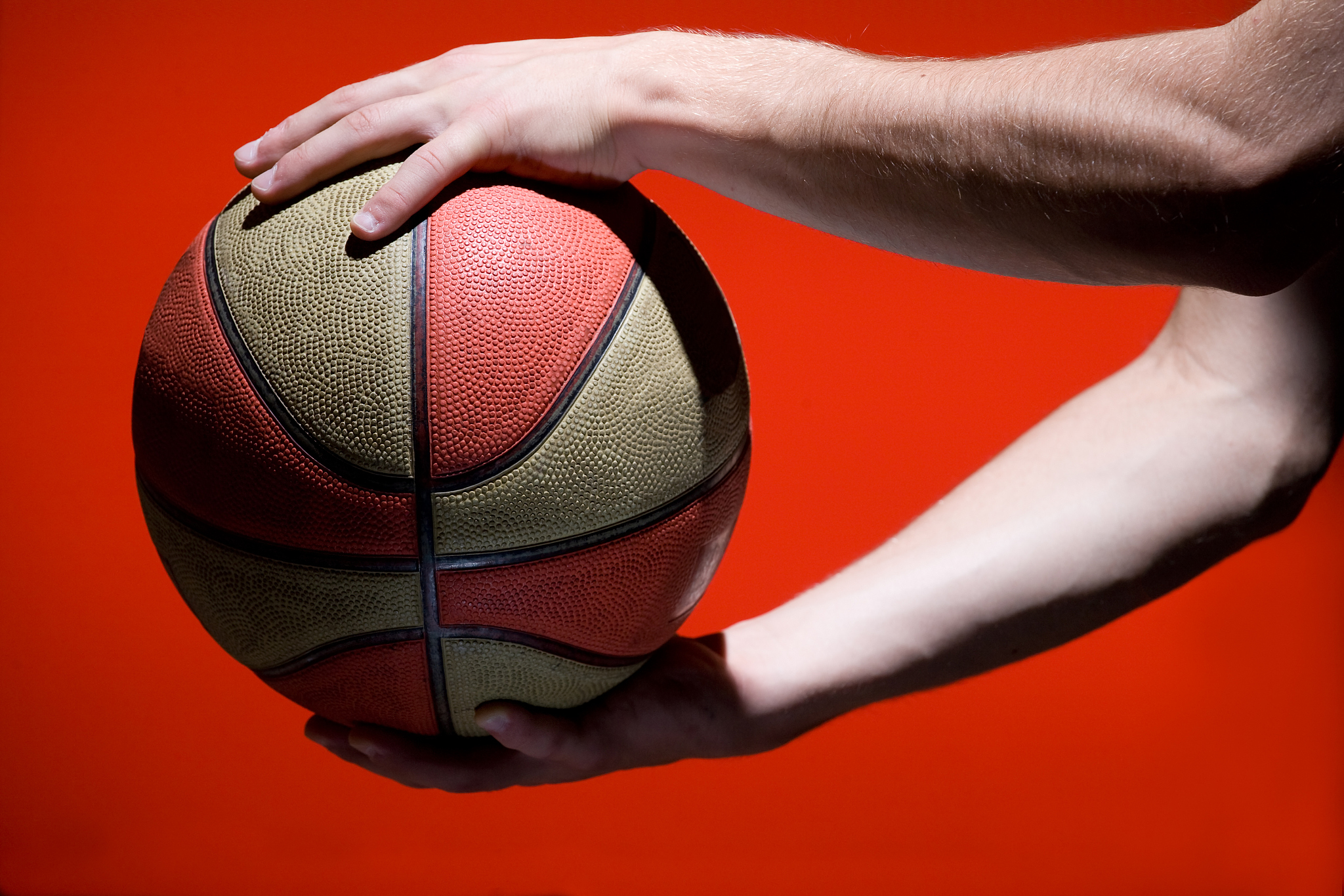 basketball ball in hands isolated on red background