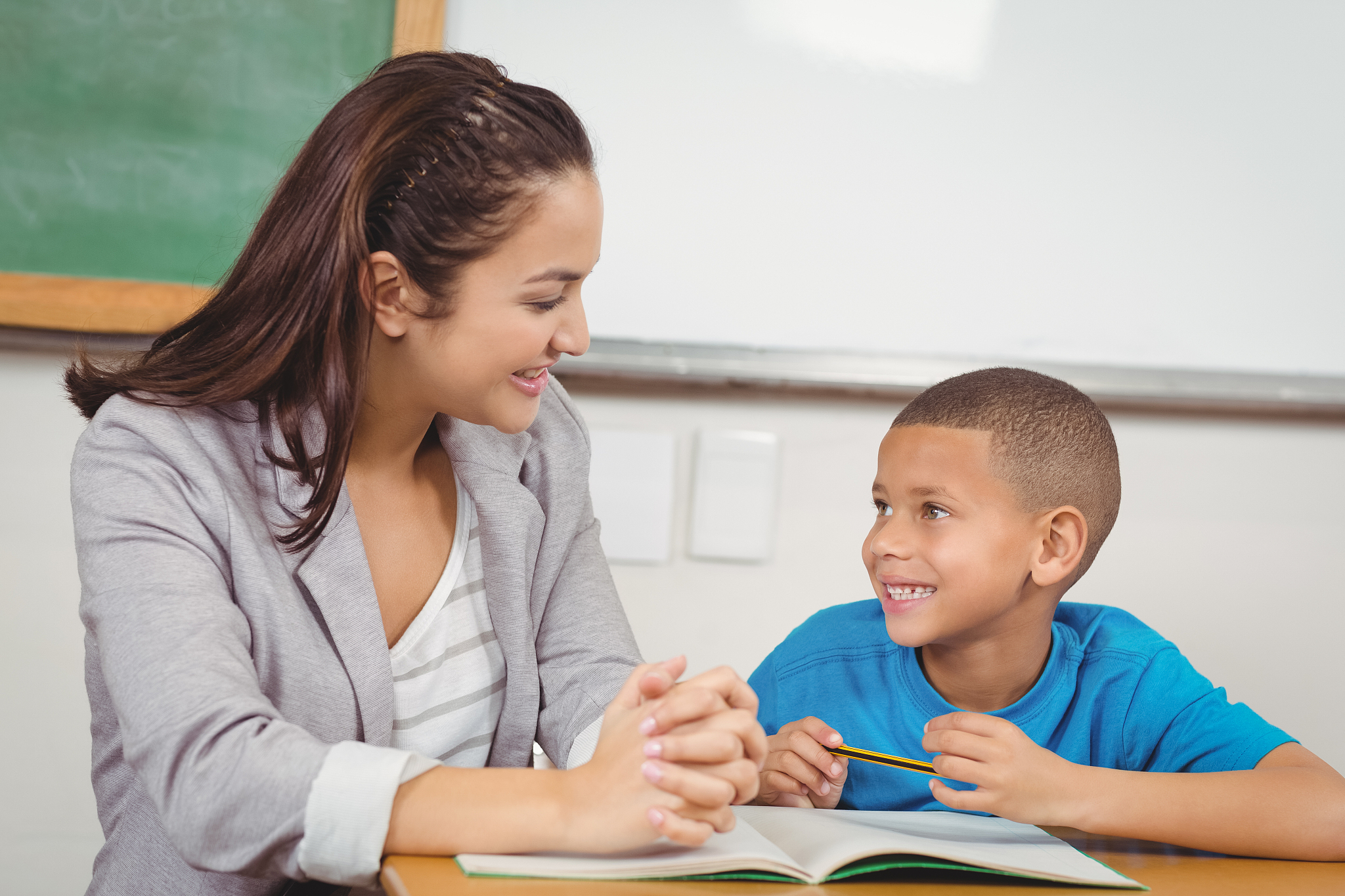 pretty teacher helping pupil at his desk