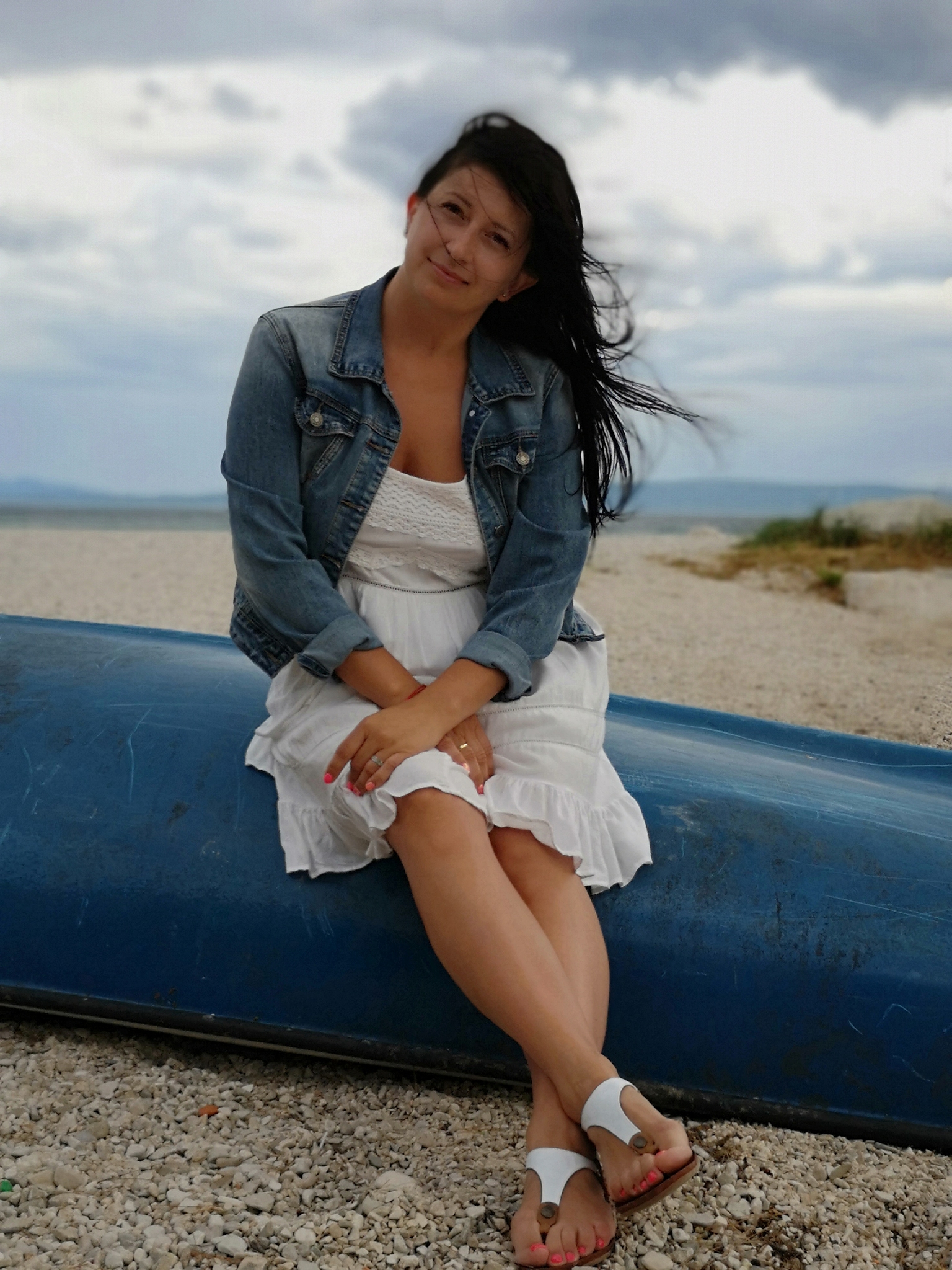 full length portrait of woman sitting at beach against sky