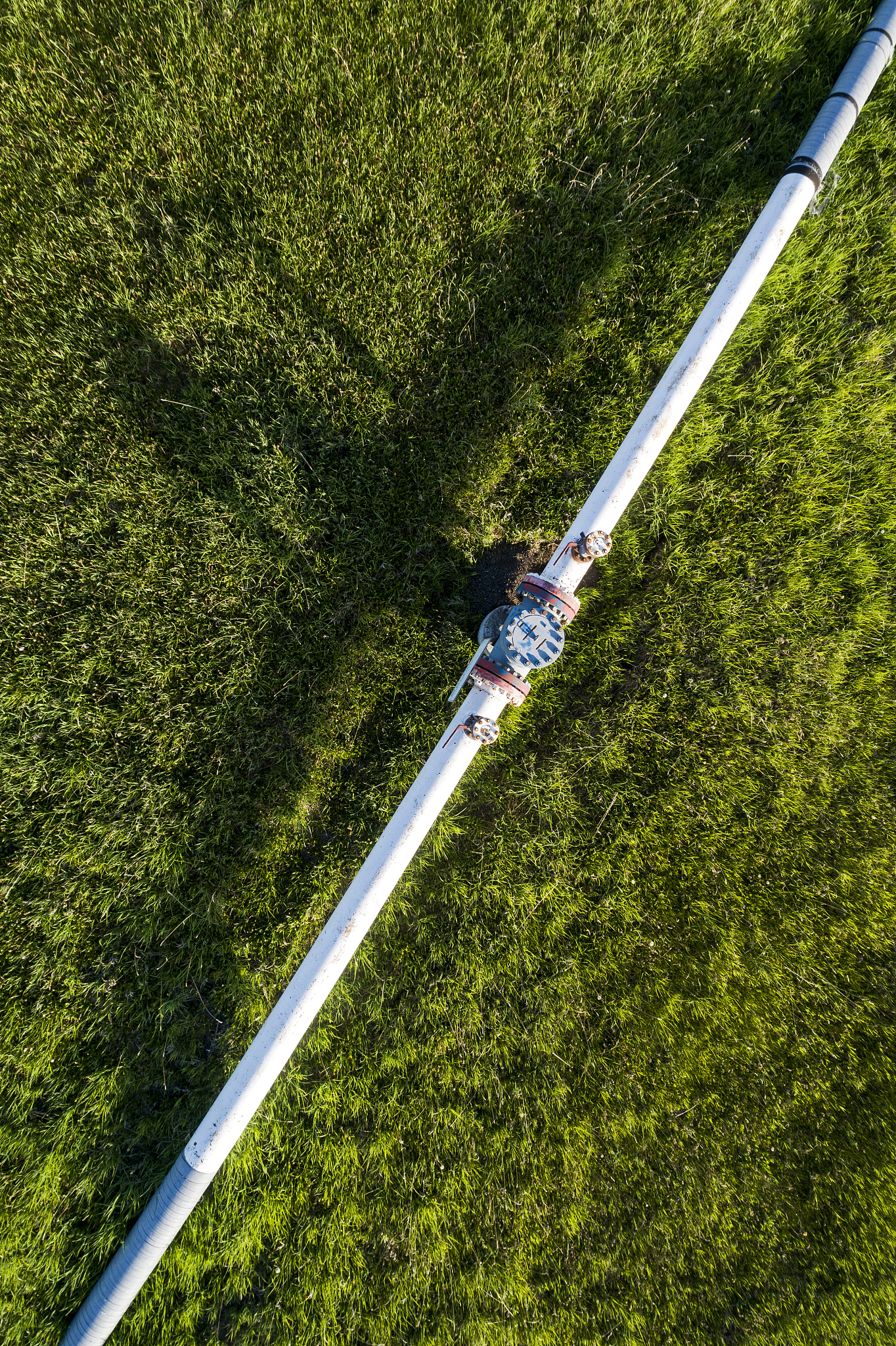 aerial view of a pipeline with a value and coupling in a green f