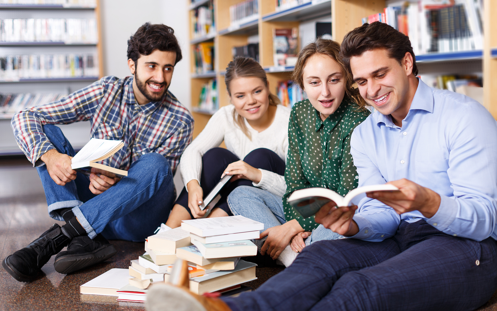 students sitting on floor in library in campus and preparing tog