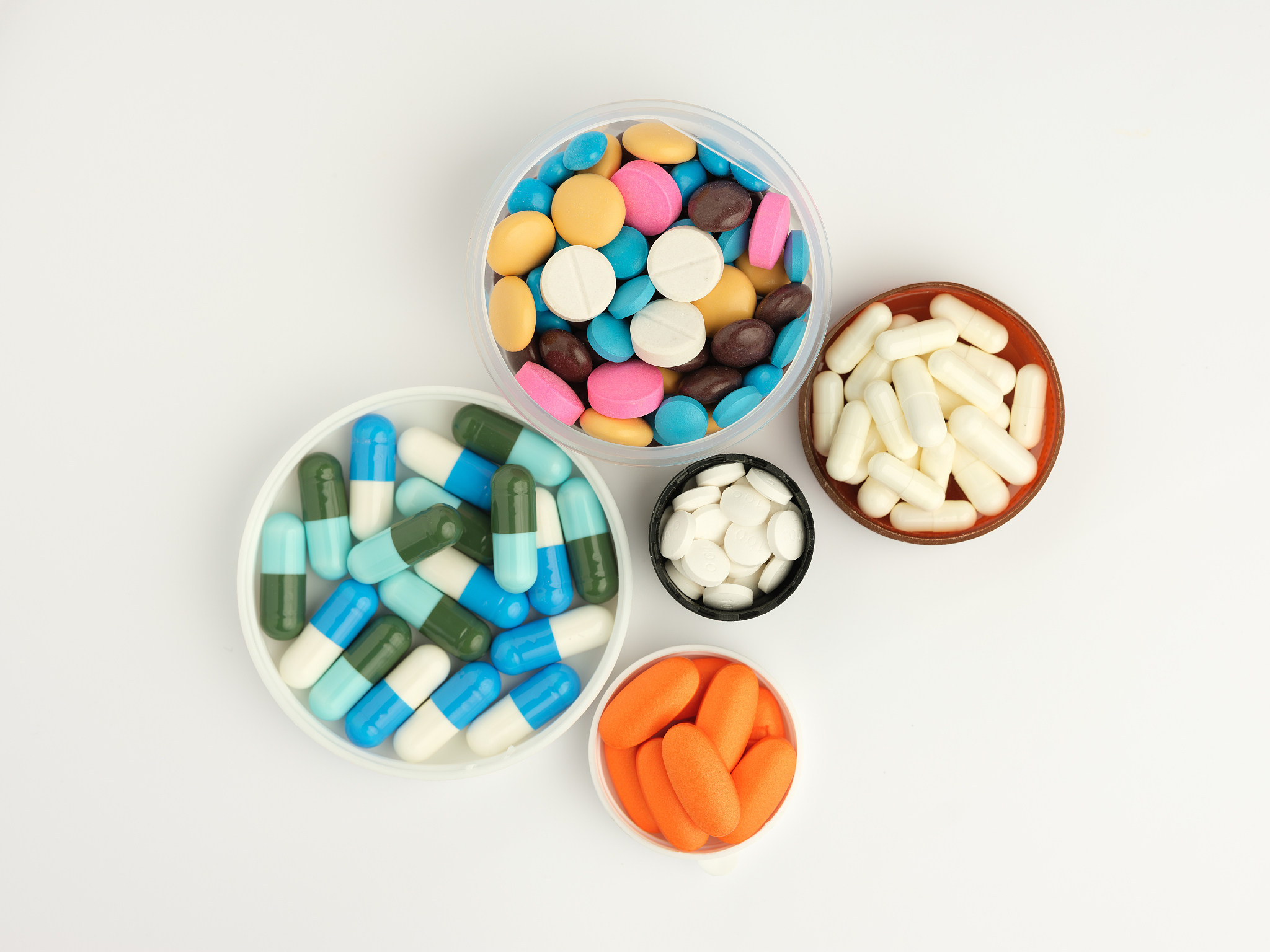 multicoloured medicines in circular containers, on white backgro