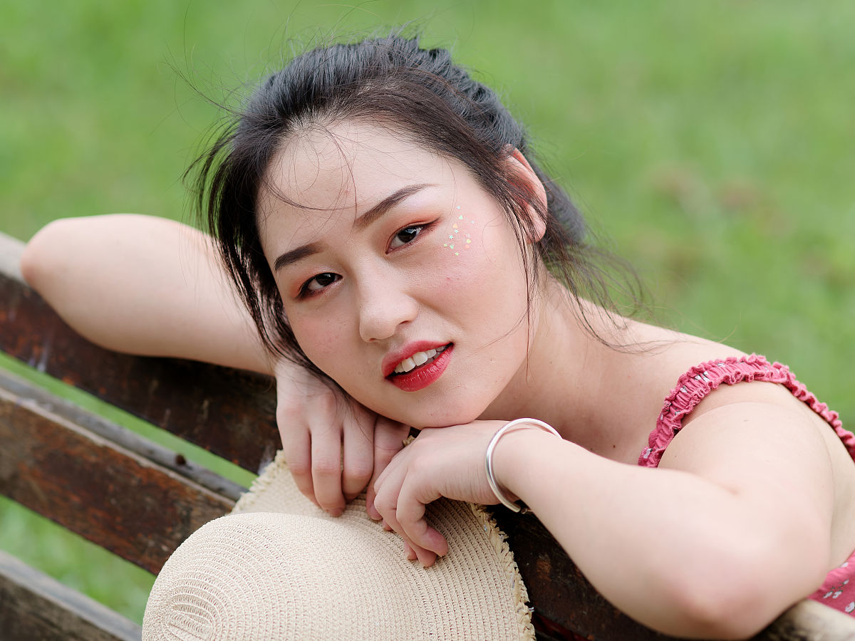 年轻的亚洲女人的肖像看着和微笑的头在她的手与自然的背景,美丽的中
